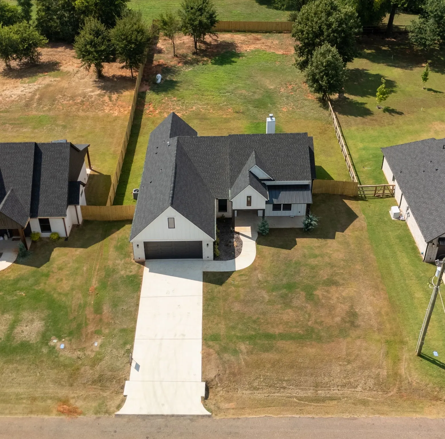 Modern farmhouse-style exterior featuring a black shingle roof, white vertical siding, and an attached two-car garage