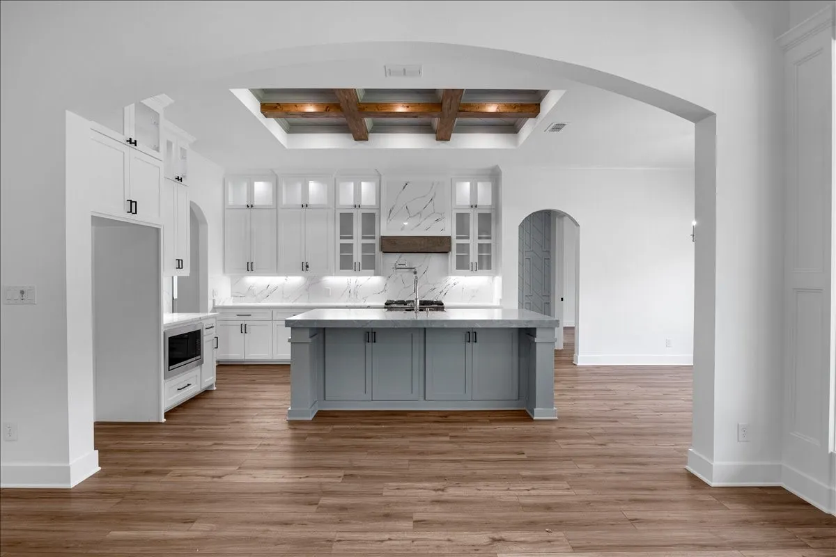 Kitchen featuring a large central island, overhead wood-beam ceiling detail, and wood-finish flooring