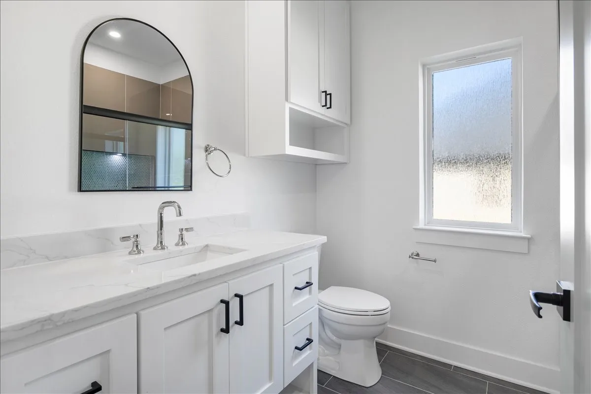 White vanity with a solid surface countertop, chrome fixtures, and black hardware