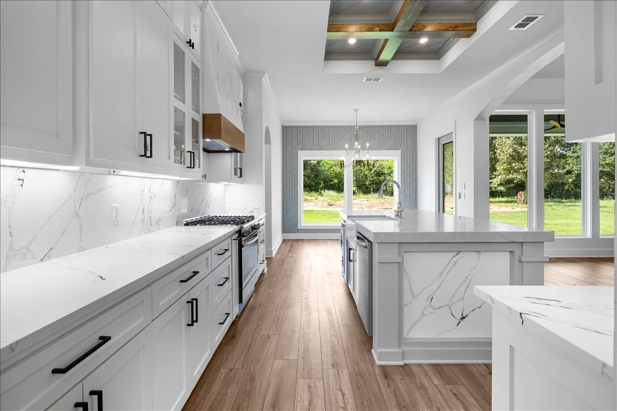 Gourmet kitchen featuring white cabinetry, integrated stainless steel appliances, stone slab countertops, a coordinating stone slab backsplash, and wood-finish flooring