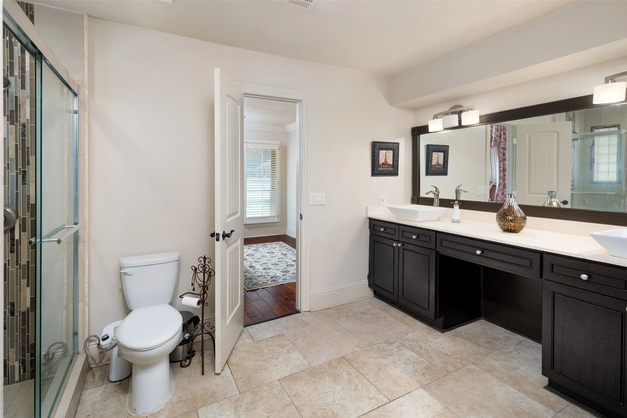 Full bathroom with double vanity, healthy amount of natural light, and a shower stall