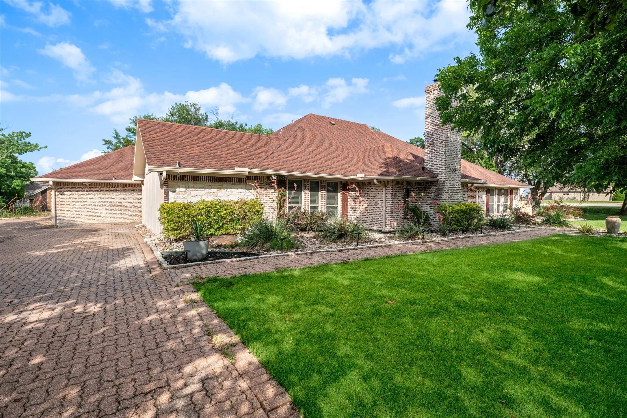 Ranch-style home with a front lawn, a chimney, brick siding, and a shingled roof
