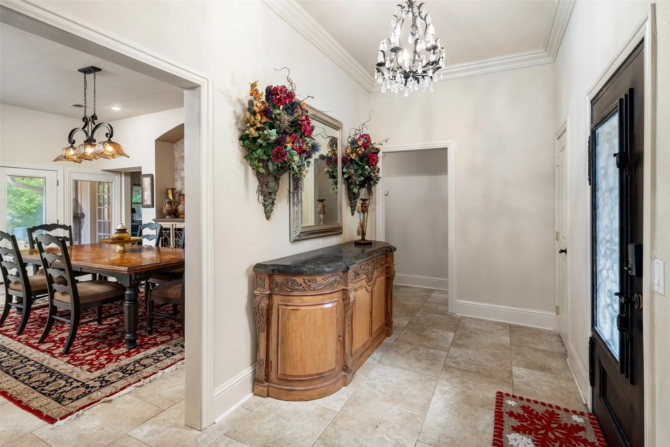 Foyer featuring a chandelier, ornamental molding, baseboards, and light tile patterned floors