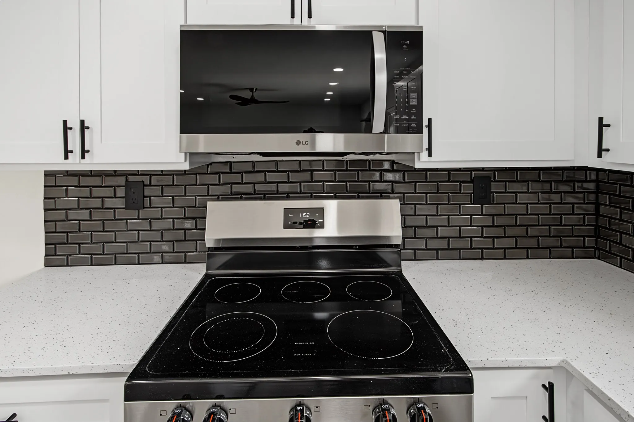 Modern kitchen featuring white cabinetry with matte black hardware, a stainless steel range, and an over-the-range microwave