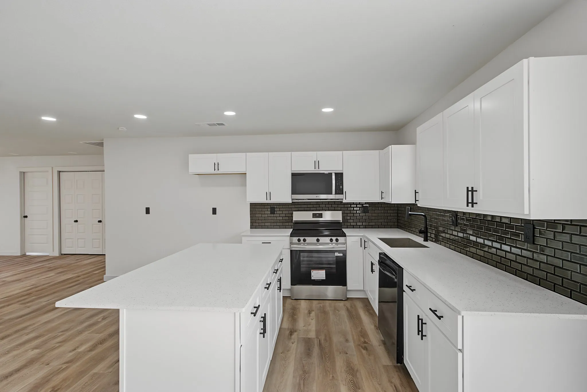 Modern kitchen featuring a U-shaped island with white cabinetry and quartz countertops