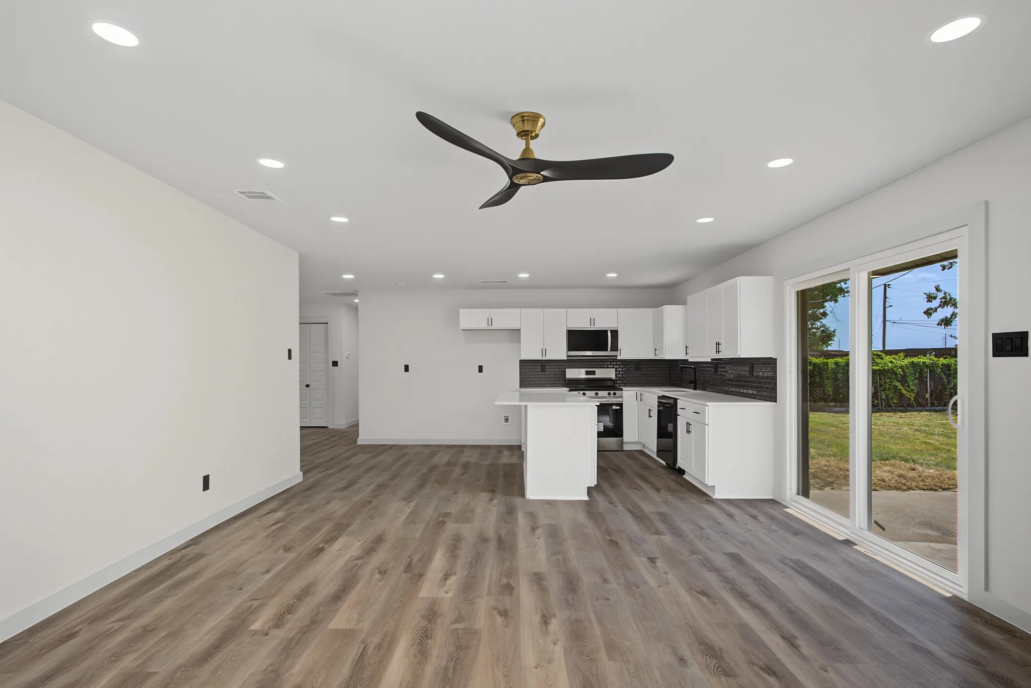 Open-concept living space featuring wood-finish flooring, recessed lighting, and a modern ceiling fan