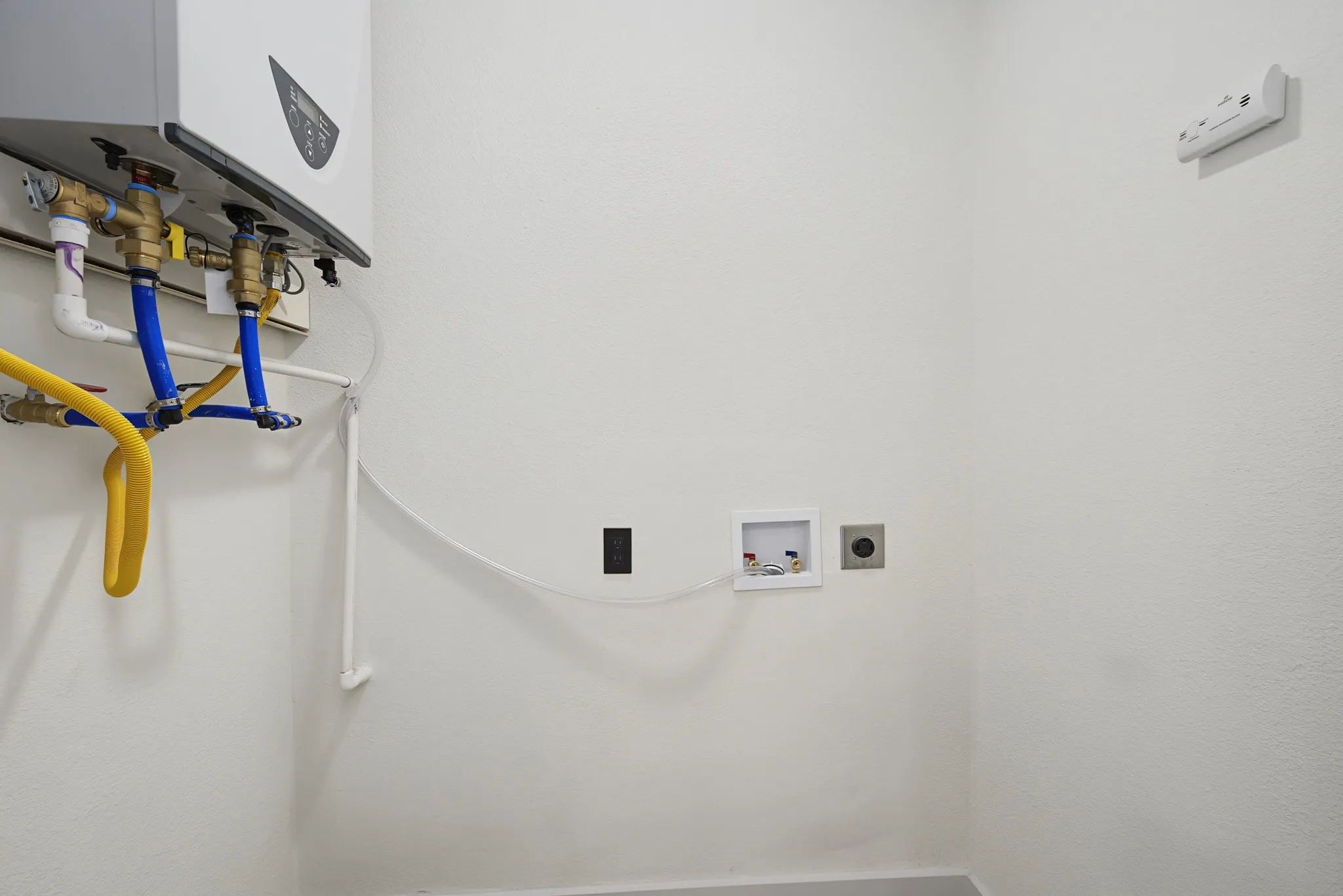 Utility area featuring a wall-mounted tankless water heater, designated washing machine hookups, and a dryer vent