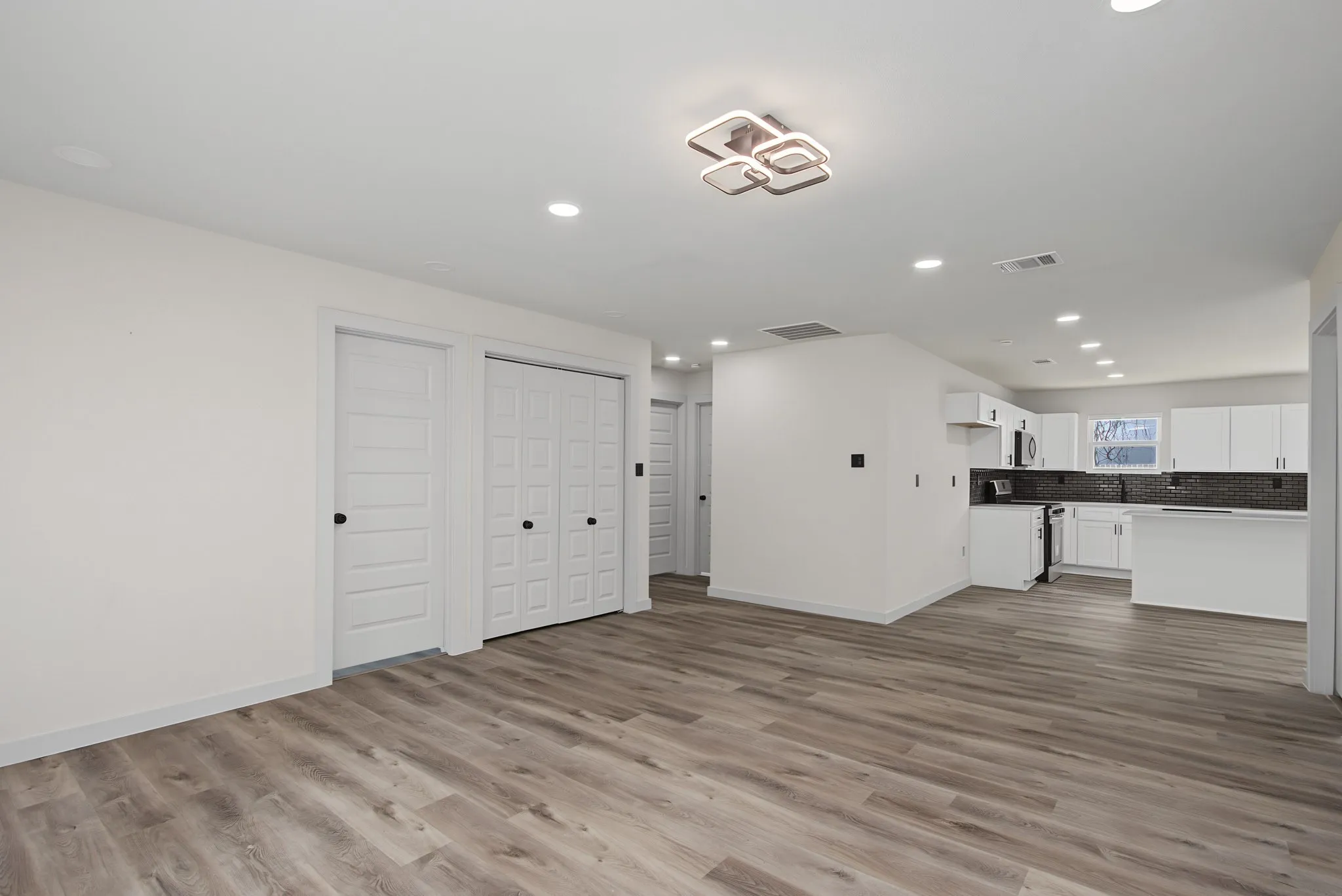 Open-concept living space featuring wood-finish flooring, recessed lighting, and a contemporary ceiling fixture