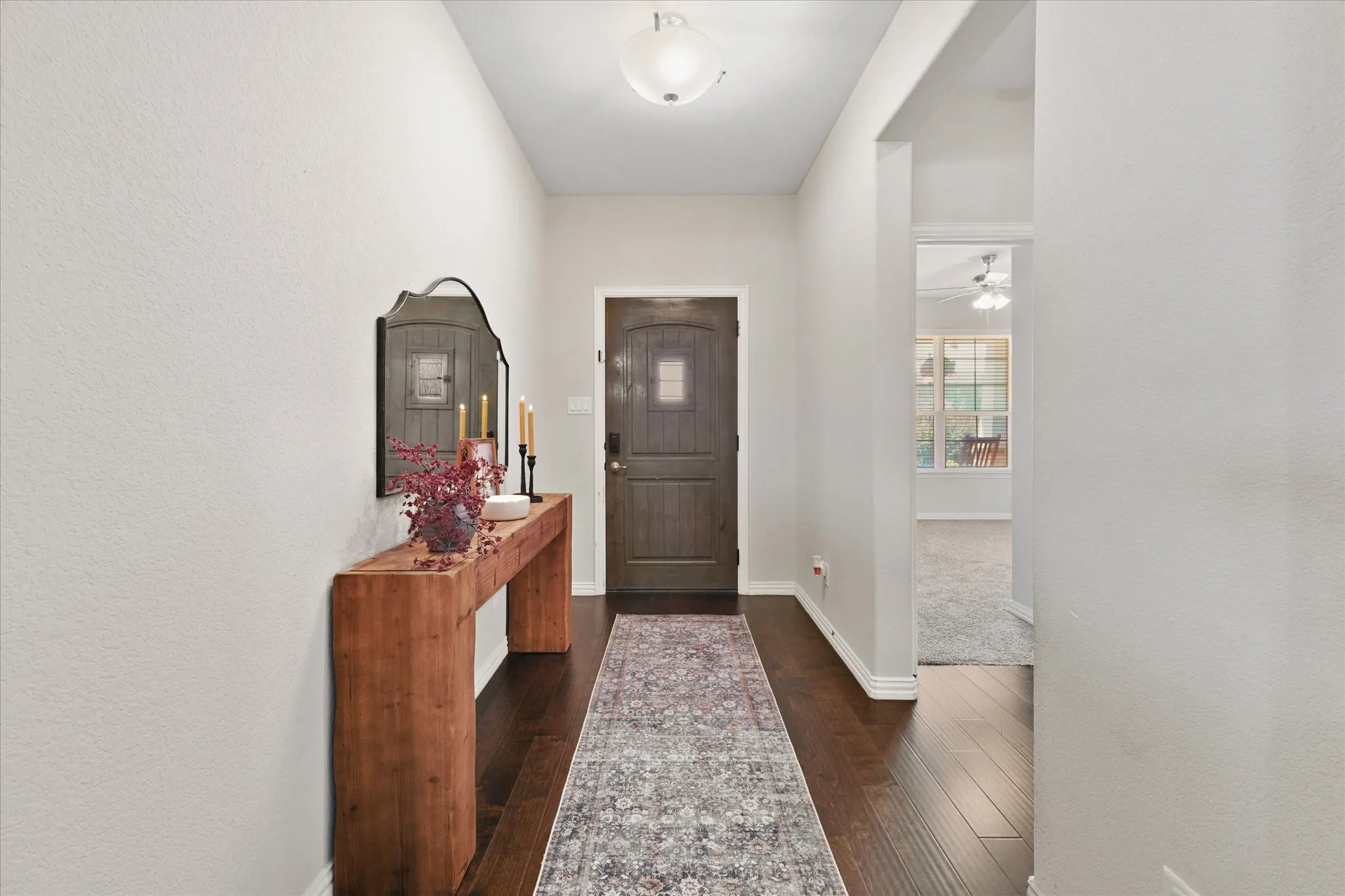Entryway featuring wood-finish flooring, a dark wood-paneled door with frosted glass, and light-colored walls