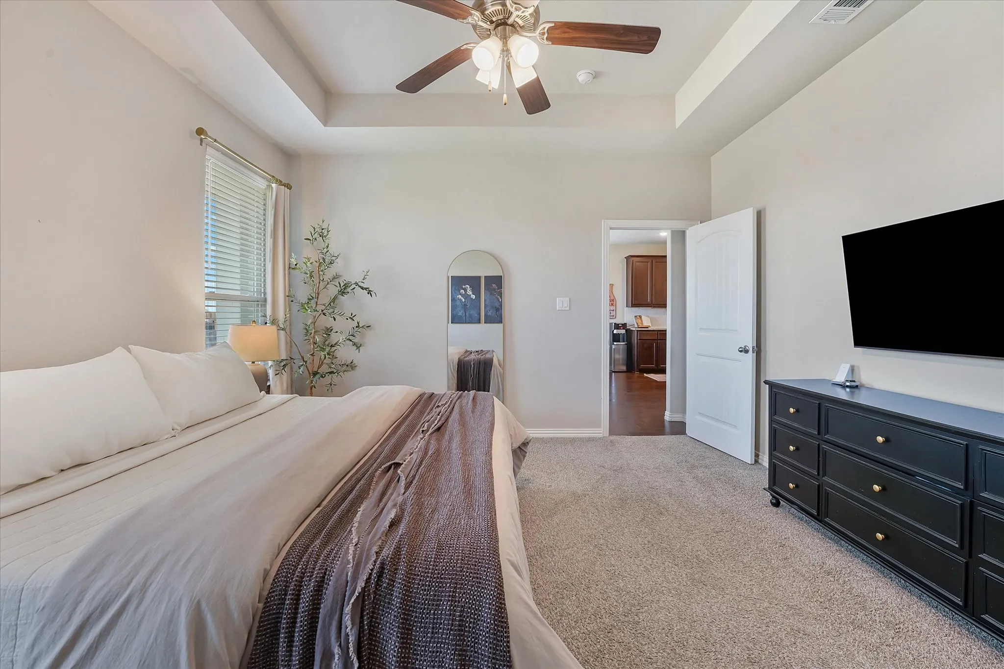 Carpeted room featuring a tray ceiling with a ceiling fan