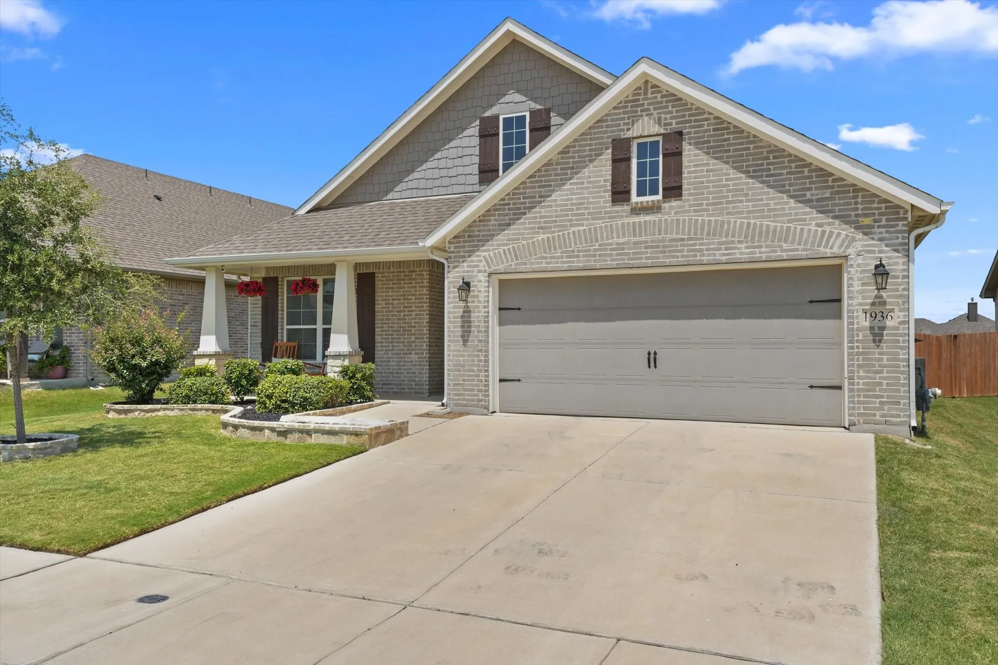 Brick and siding exterior featuring a two-car garage with a decorative light fixture