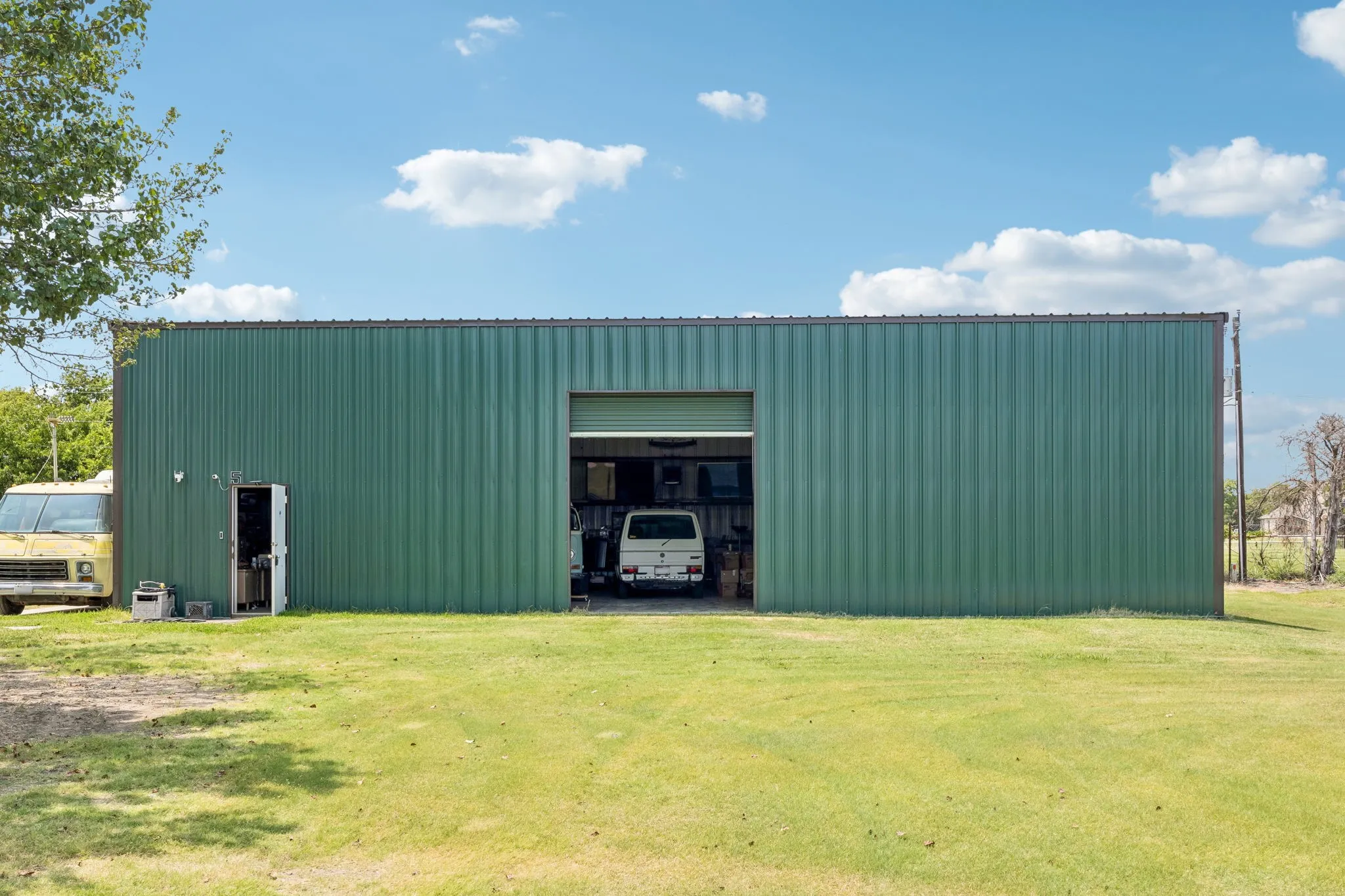 Expansive green metal-sided building with a large roll-up door and a standard entry door