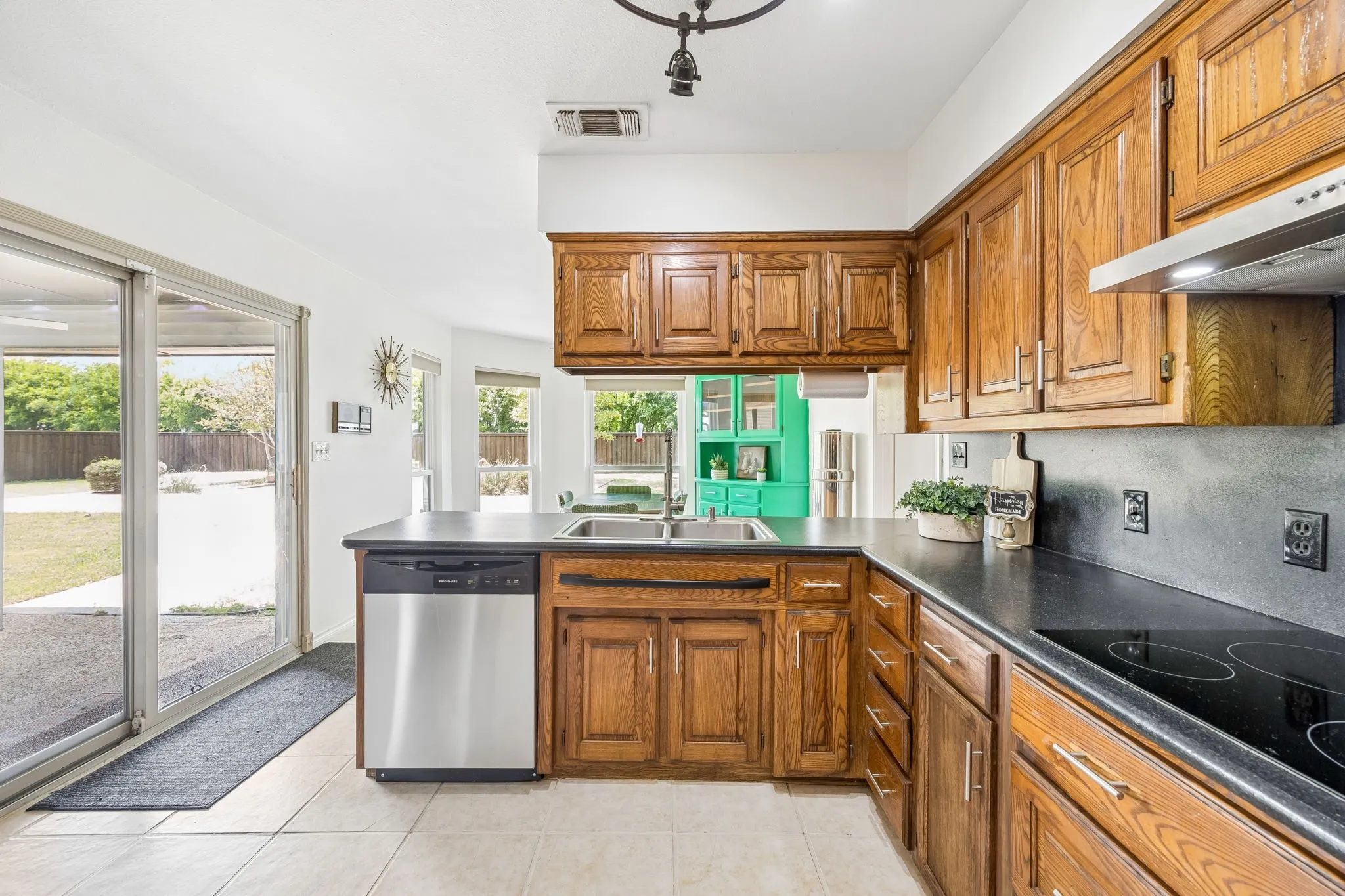Spacious kitchen featuring warm wood cabinetry and dark countertops