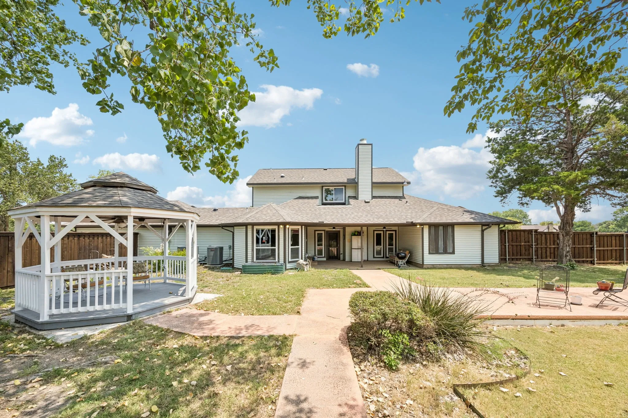 Expansive backyard featuring a white gazebo with a dark shingle roof, a concrete patio area, and a privacy fence