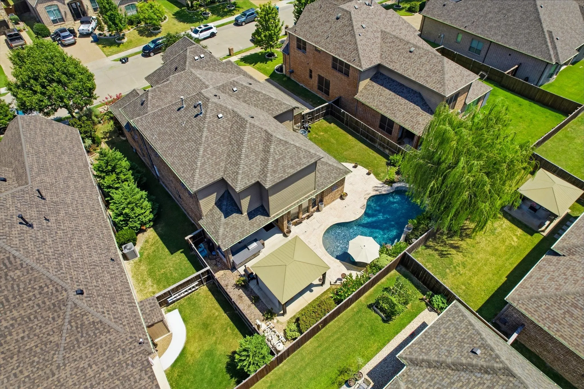 Expansive backyard oasis featuring a resort-style saltwater pool with integrated spa, travertine decking, mature landscaping with specimen trees, and manicured lawn