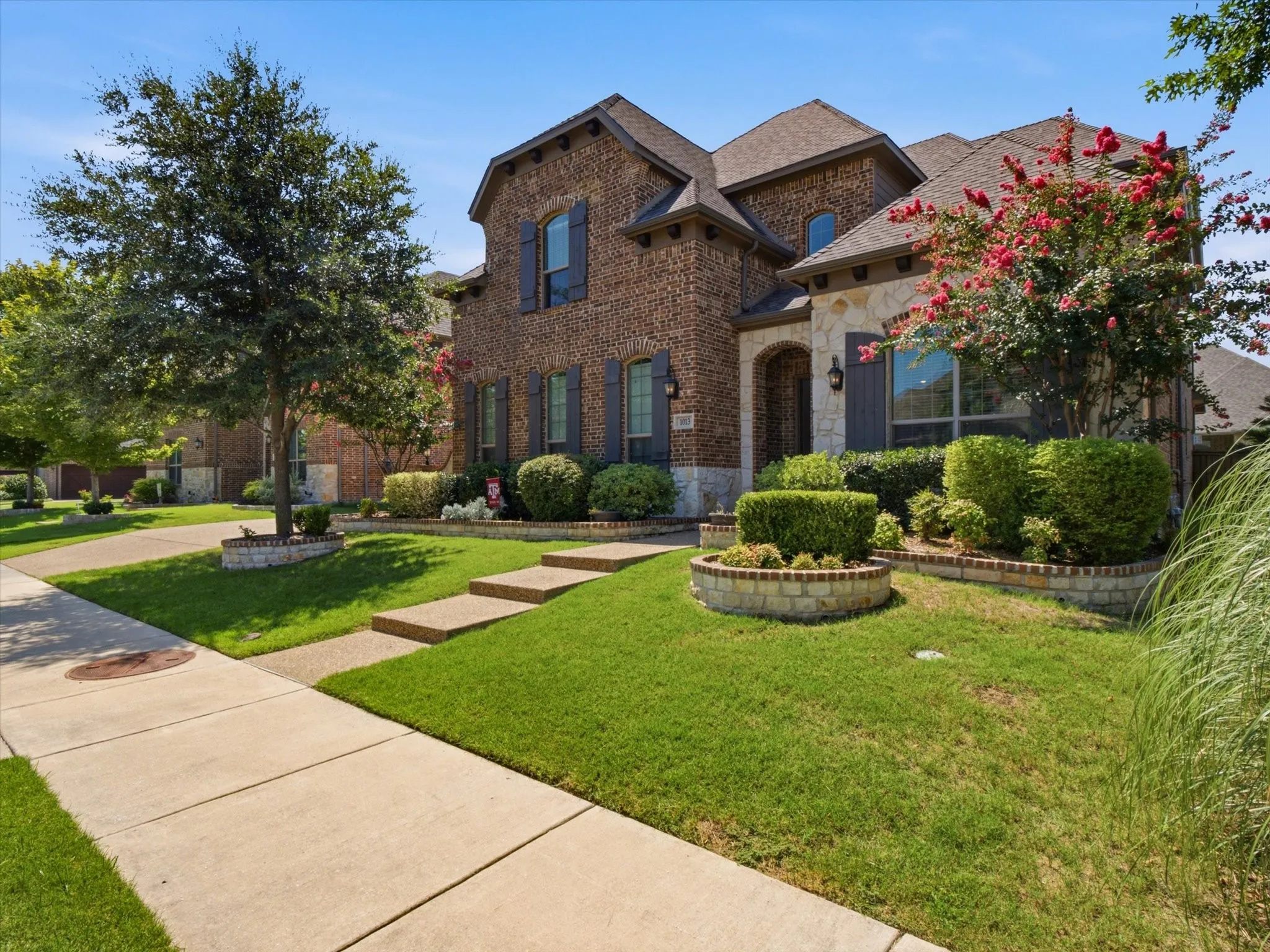 Traditional brick and stone facade featuring arched entryways, dark shutters, and a multi-level roofline