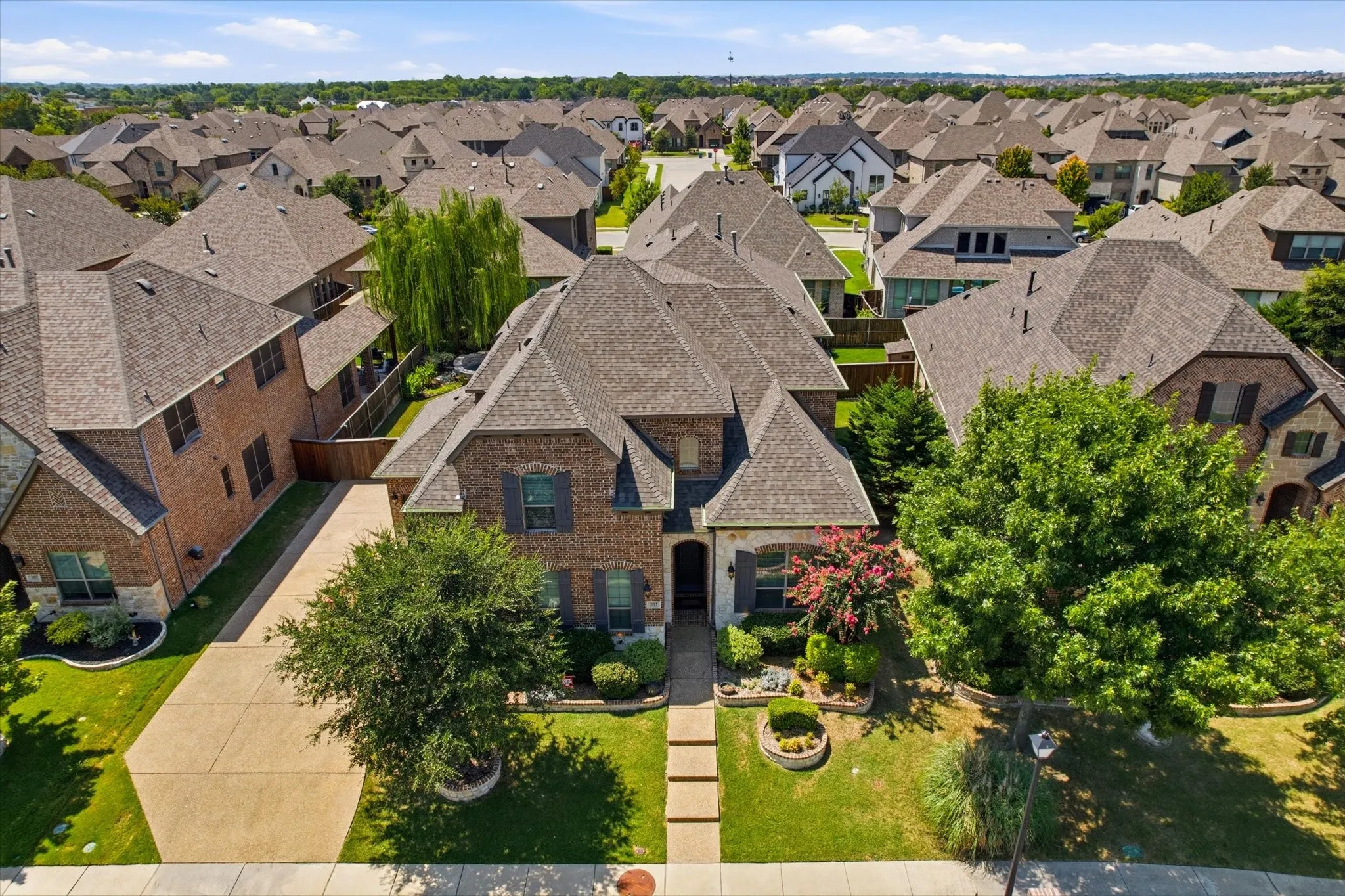 Elegant brick residence with a manicured front lawn, mature landscaping, and a welcoming stone entry pathway