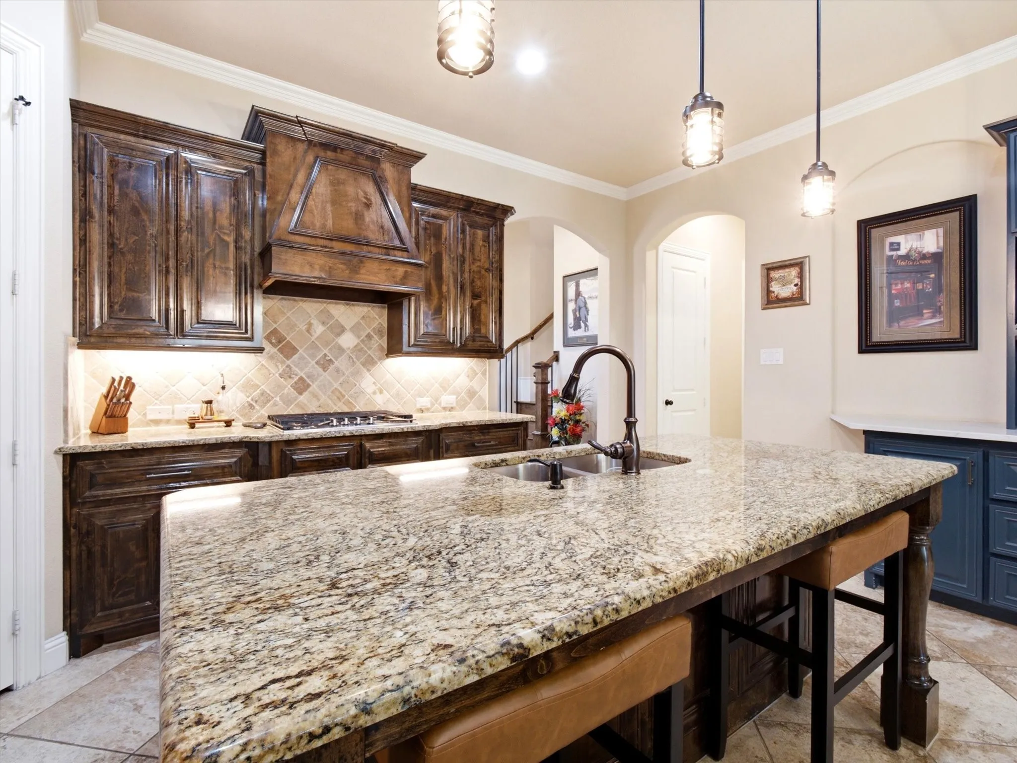Gourmet kitchen featuring dark wood cabinetry with decorative crown molding, a tile backsplash, and stainless steel gas cooktop
