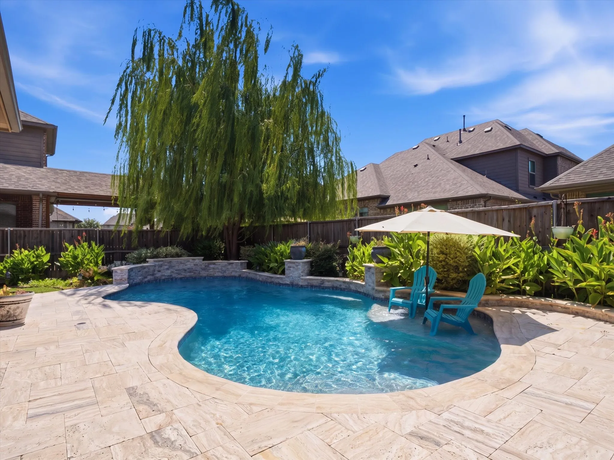 Curved inground pool with a natural stone, gazebo and a stone-clad raised spa