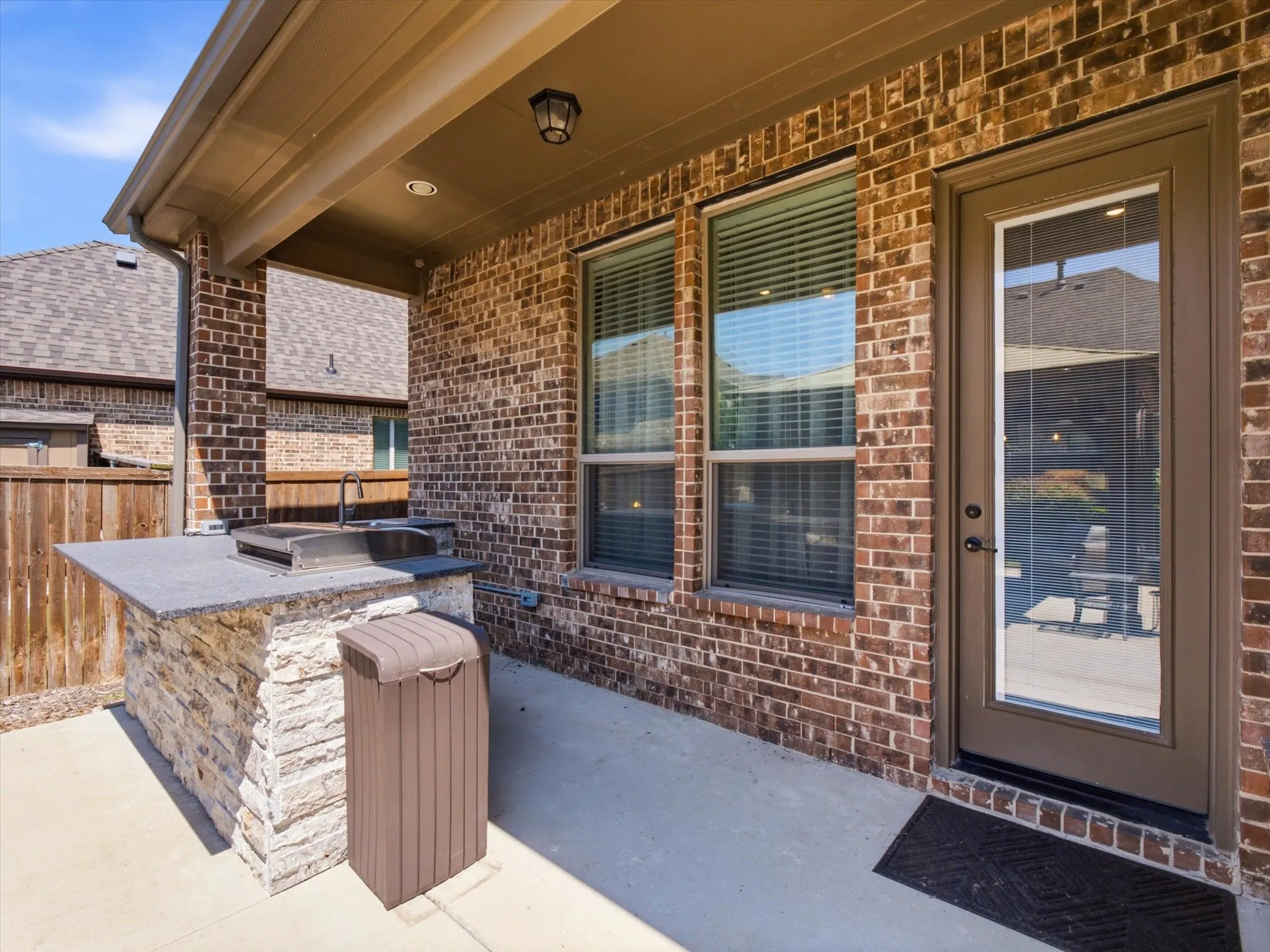 Covered patio featuring an outdoor kitchen with a built-in sink and grill, stone-stacked base, and a durable countertop all brand new.