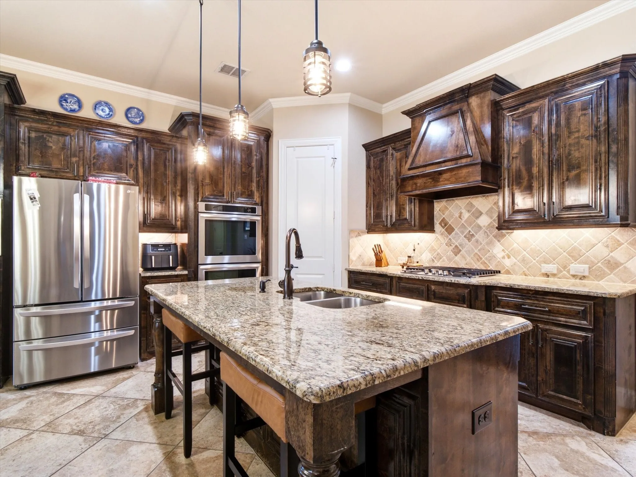 Kitchen featuring granite countertops, dark wood-finish cabinetry, stainless steel appliances, a tiled backsplash, and recessed and pendant lighting