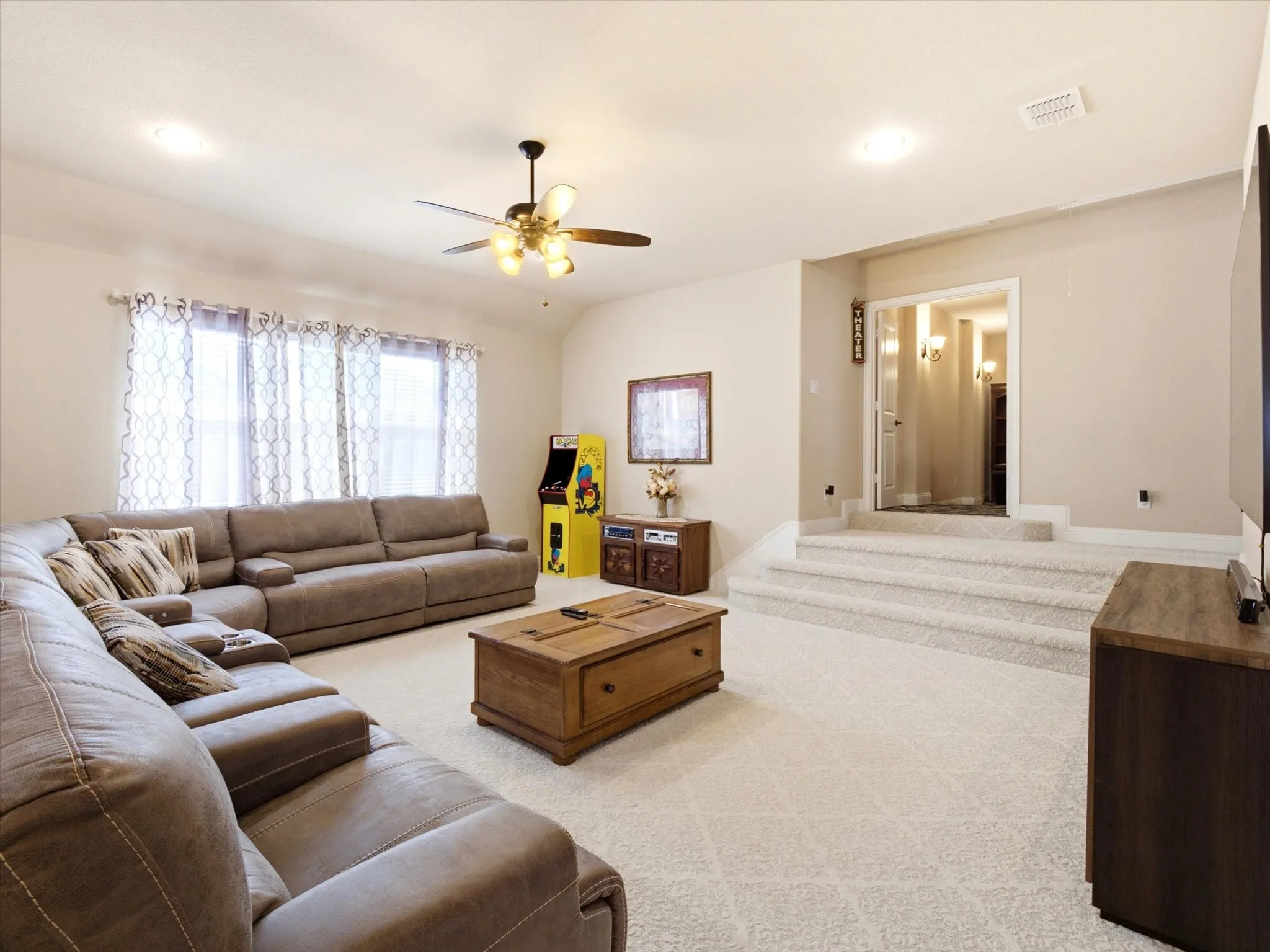 Carpeted entertainment space featuring tiered flooring, recessed lighting, and a ceiling fan