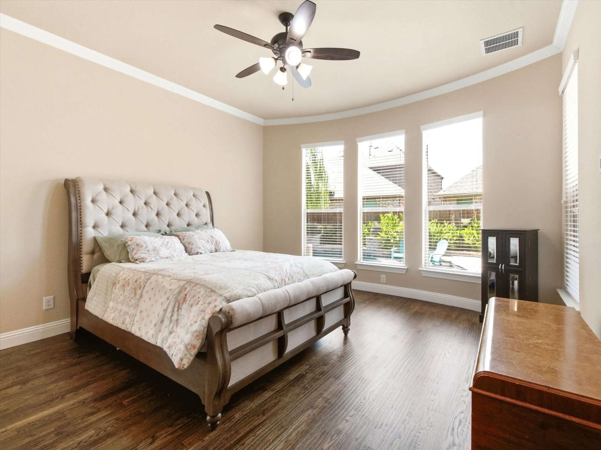 Wood-finish flooring throughout, featuring a multi-light ceiling fan and crown molding