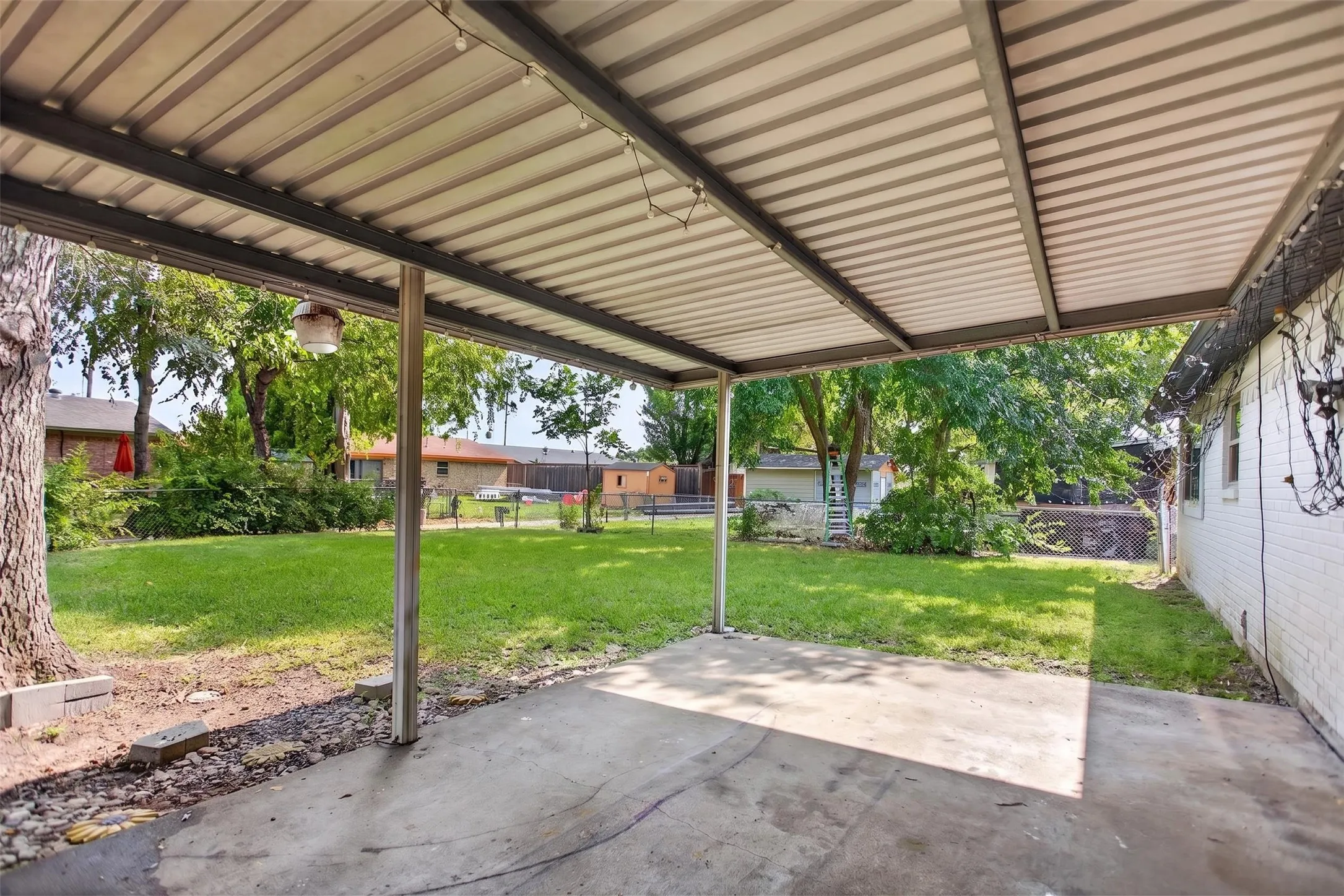 Covered patio with a concrete slab, metal roofing, and string lighting