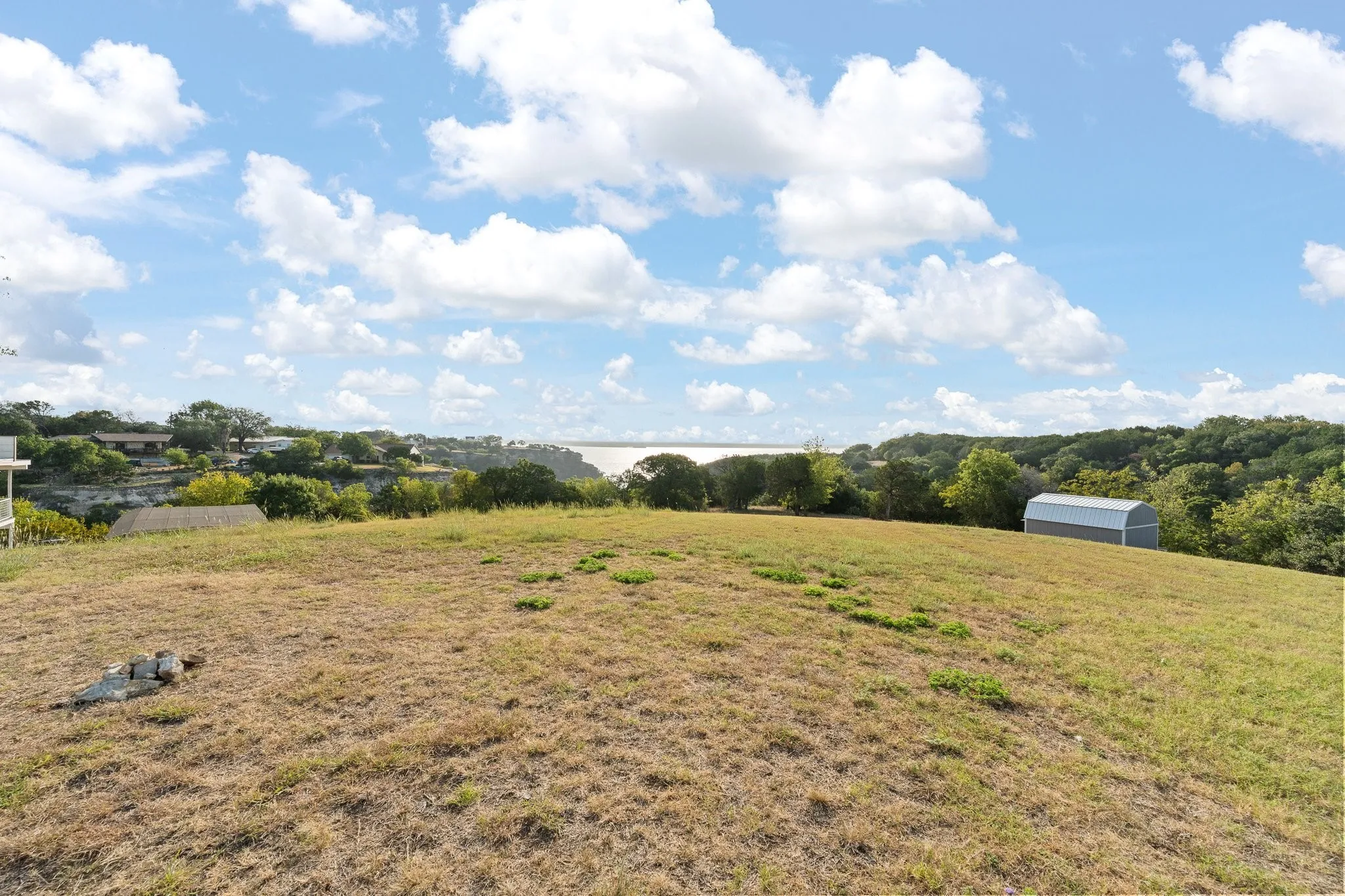 Expansive grassy terrain with a distant water body and a separate structure