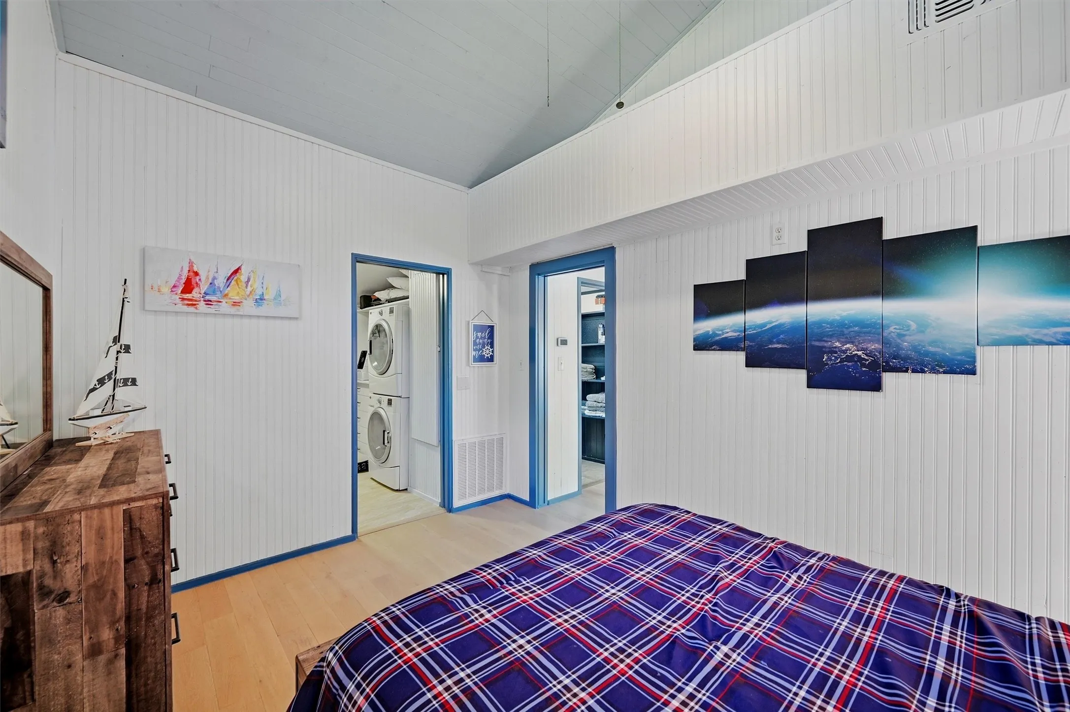 Vaulted ceiling, wood-finish flooring, white paneled walls, and two built-in doorways