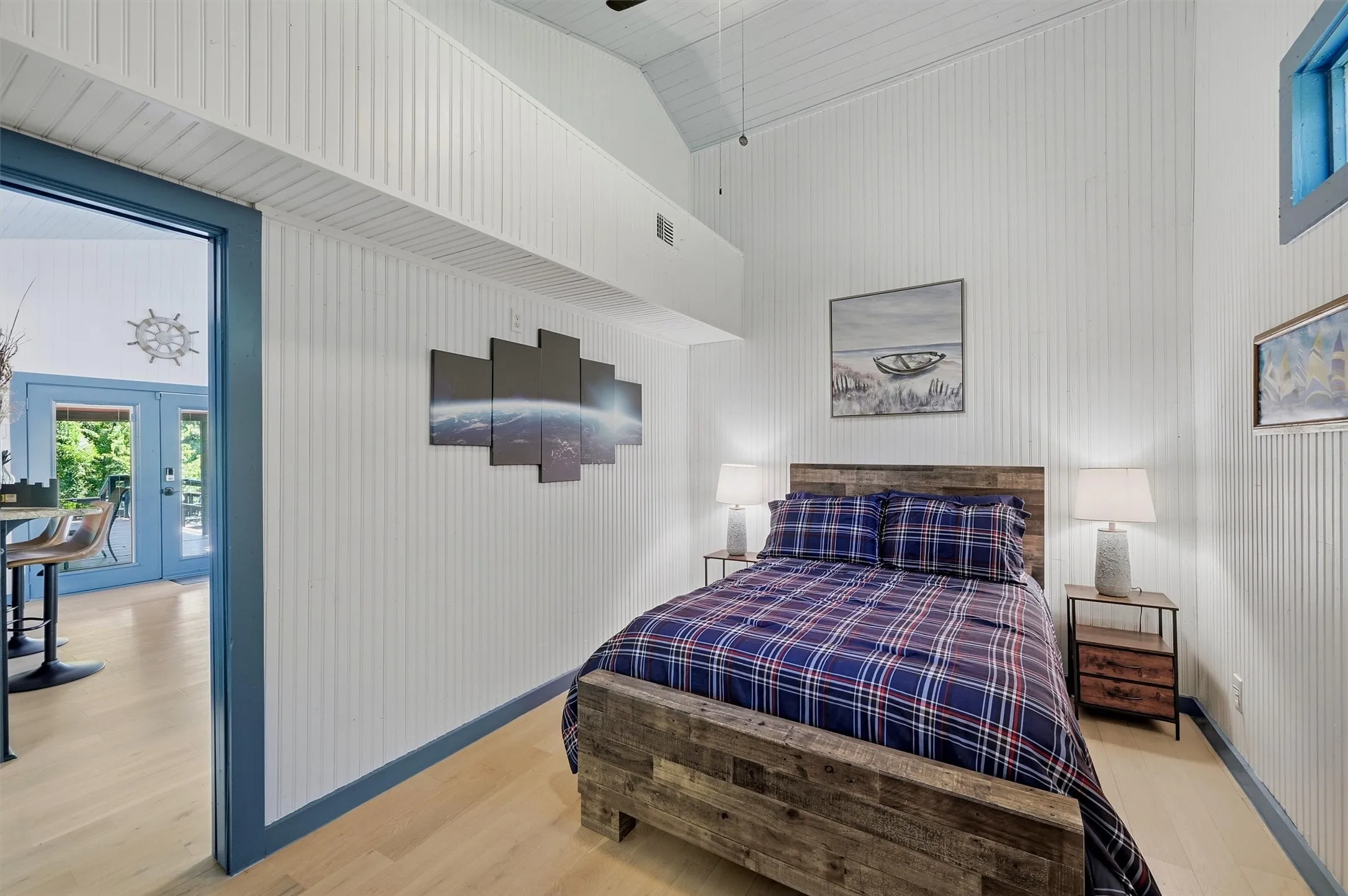 Vaulted ceiling, beadboard wall paneling, light wood-finish flooring, accent trim, and a built-in window frame