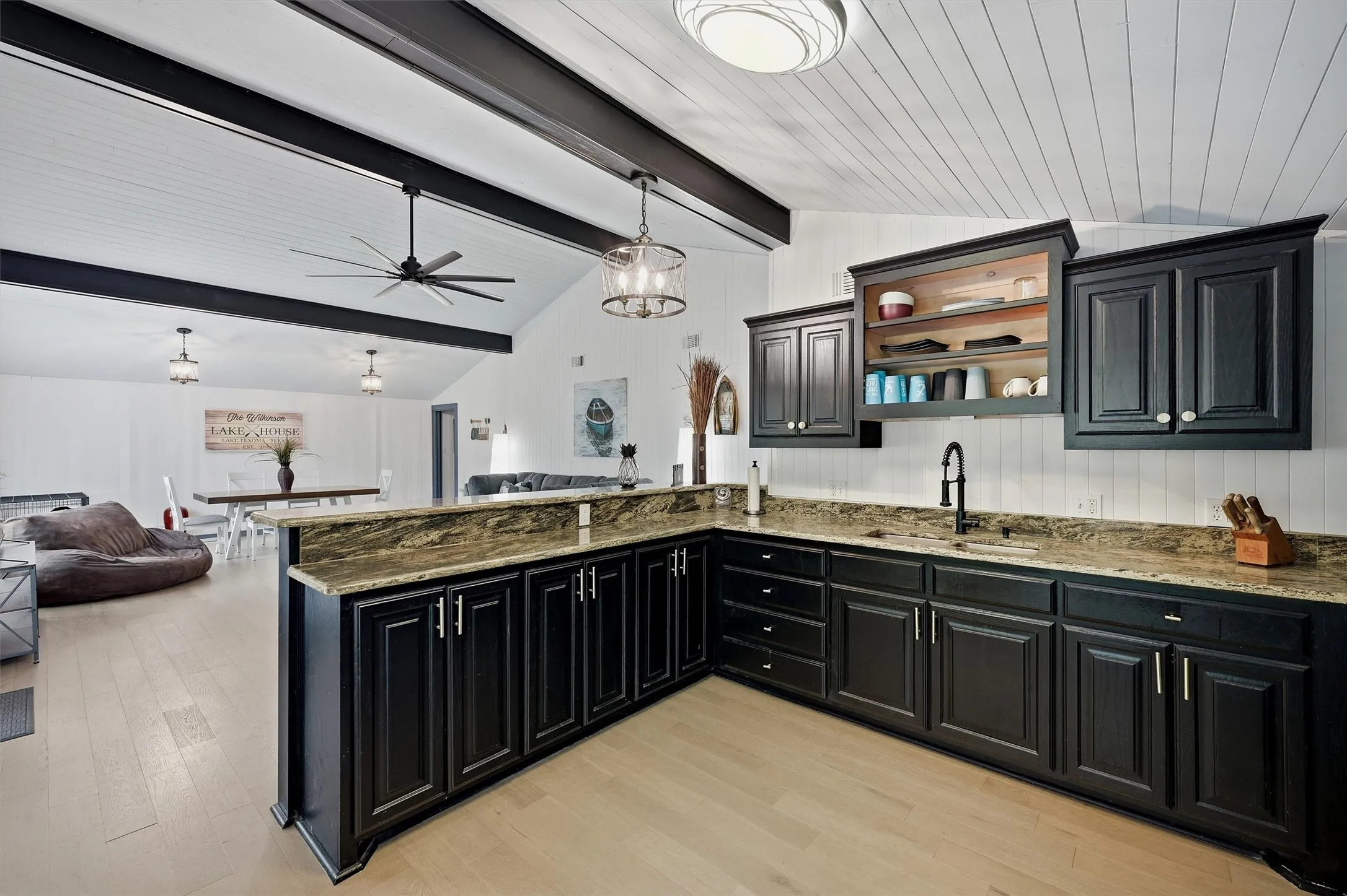 Open-concept kitchen featuring dark cabinetry, speckled countertops, and a black faucet