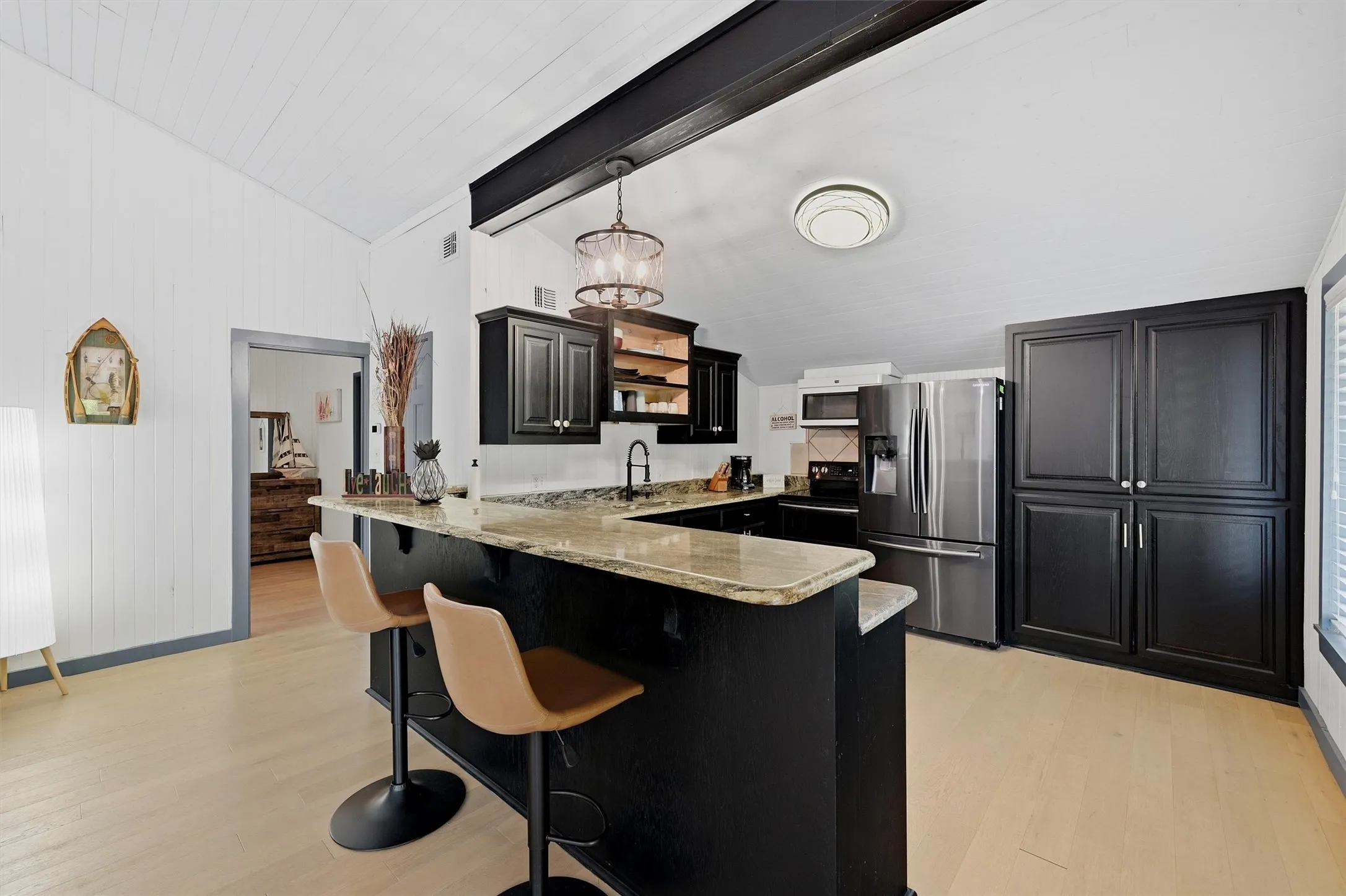 Kitchen featuring dark cabinetry, stainless steel appliances, light-toned countertops, and wood-finish flooring