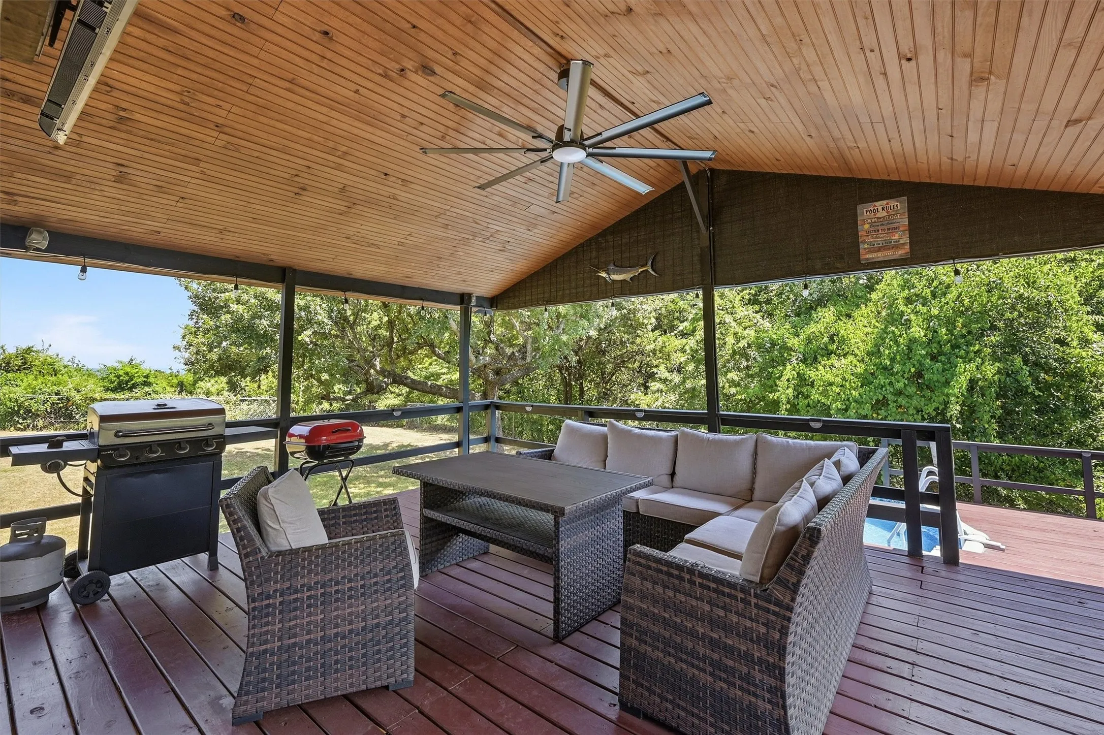 Expansive covered deck featuring a wood plank ceiling and a large ceiling fan