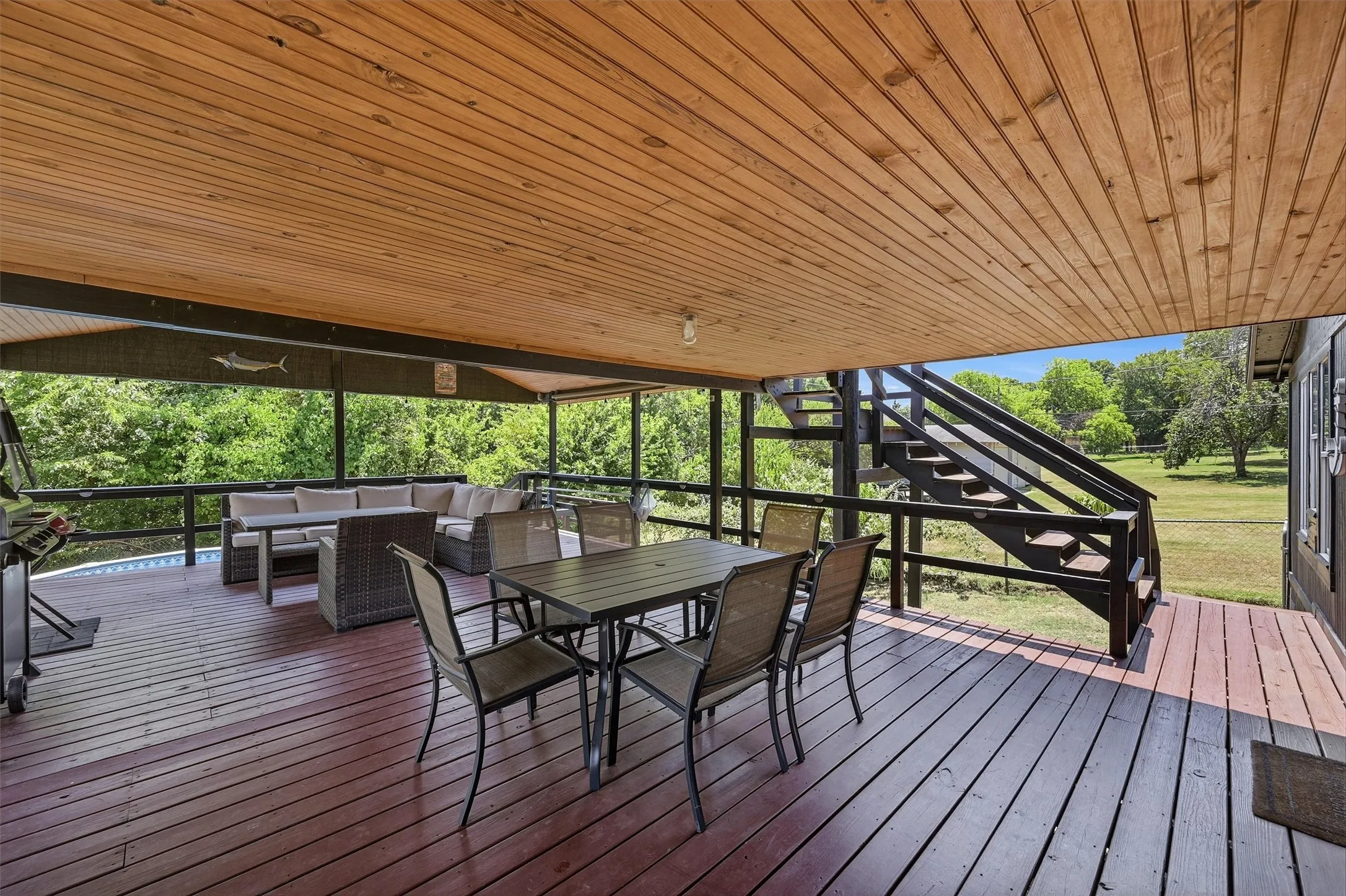 Expansive covered deck with wood plank flooring and a slatted wood ceiling