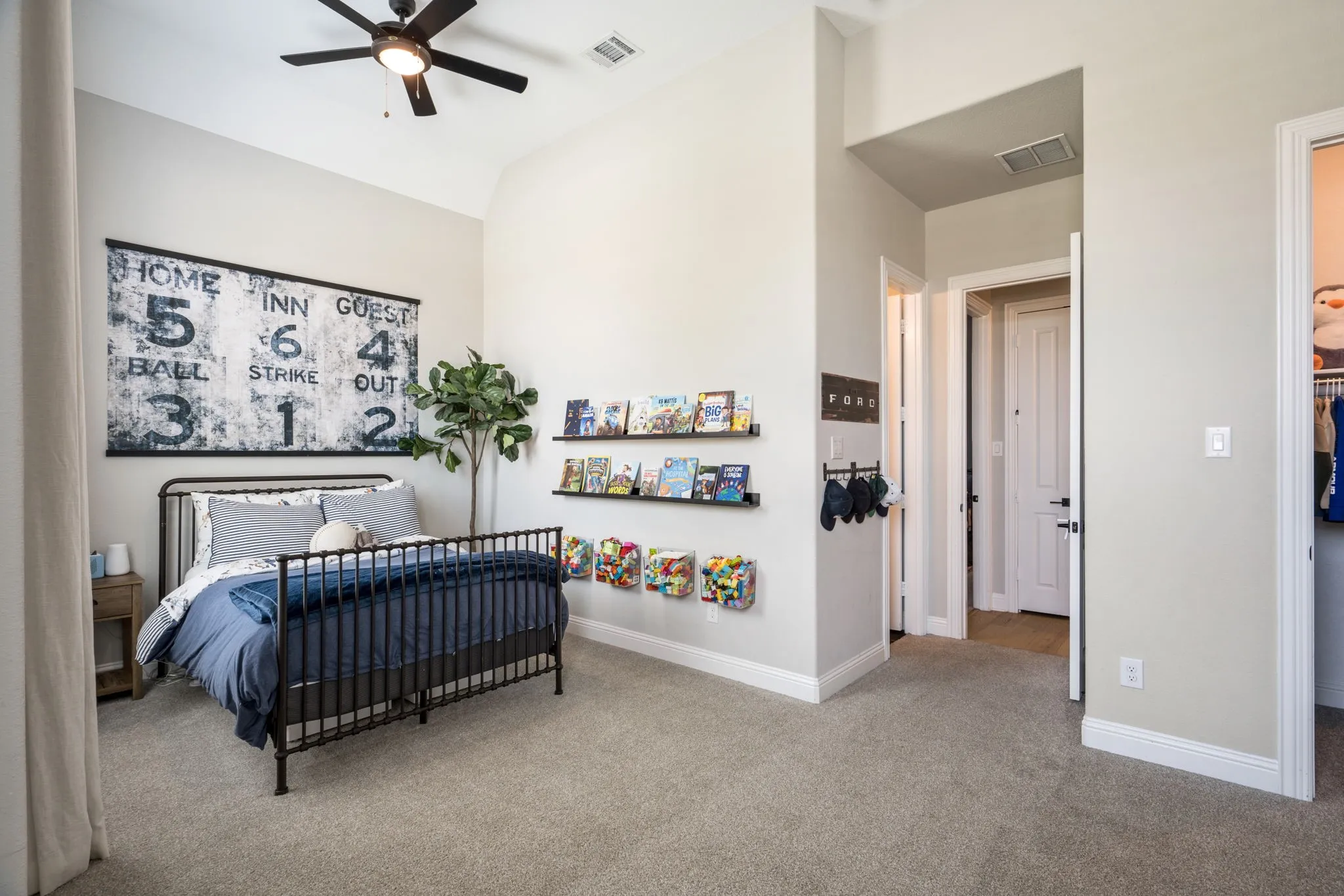 Spacious secondary bedroom featuring a black metal bed frame, carpet flooring, and ample natural light from recessed ceiling fixtures and a ceiling fan