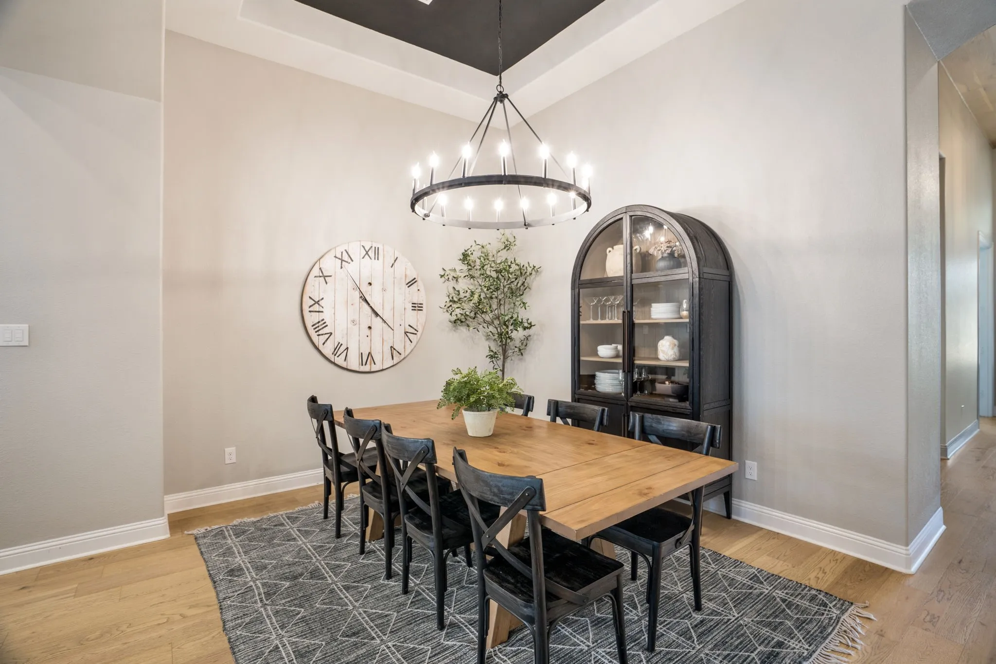 Formal dining area featuring a tray ceiling with a dark accent, hardwood-finish flooring, and a large circular chandelier