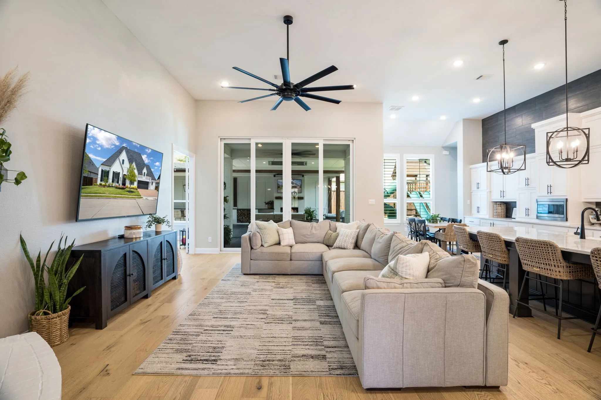 Open-concept living area featuring a sectional sofa arrangement, wood-finish flooring throughout, and a neutral area rug
