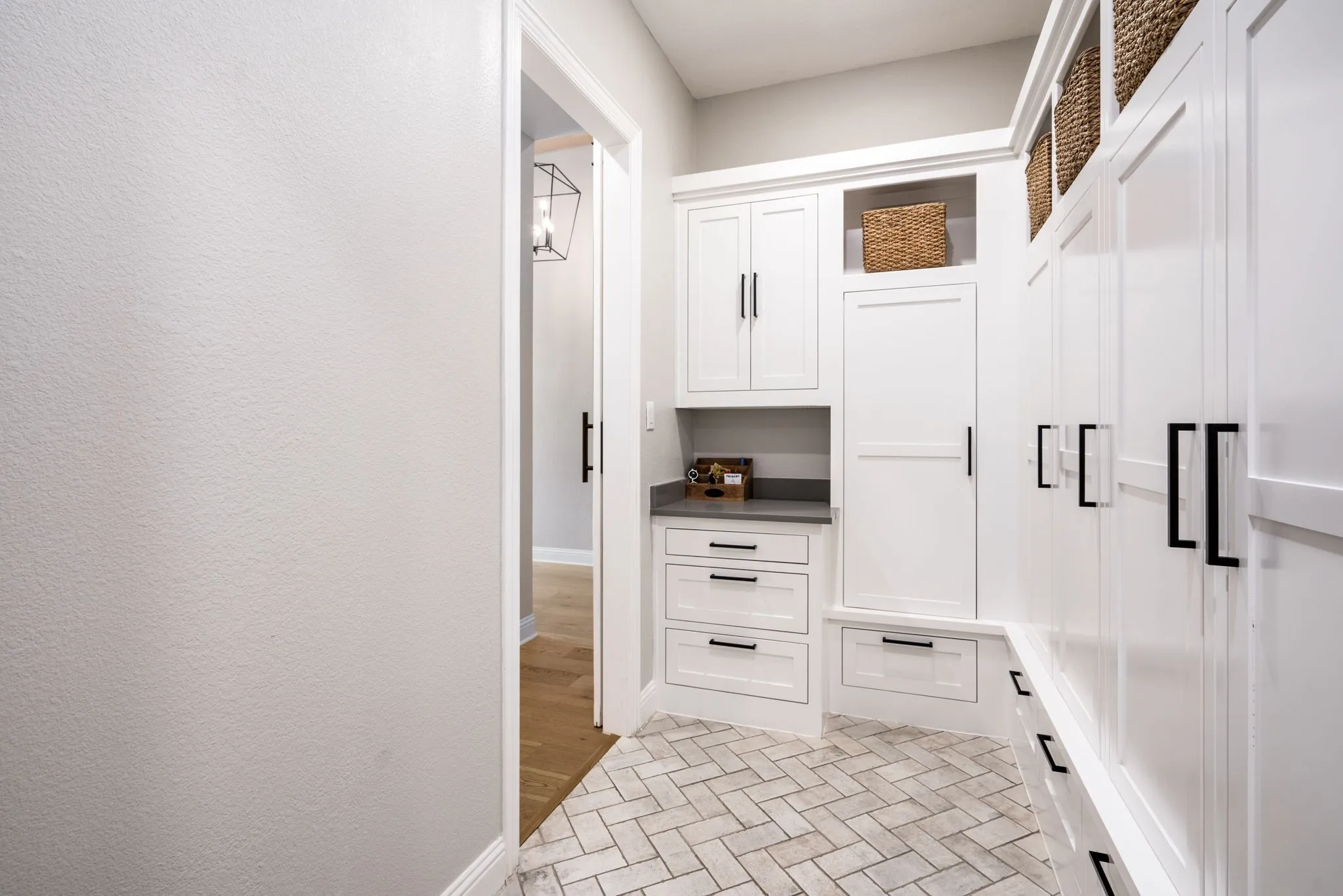 Herringbone tile flooring complementing extensive built-in white cabinetry with matte black hardware