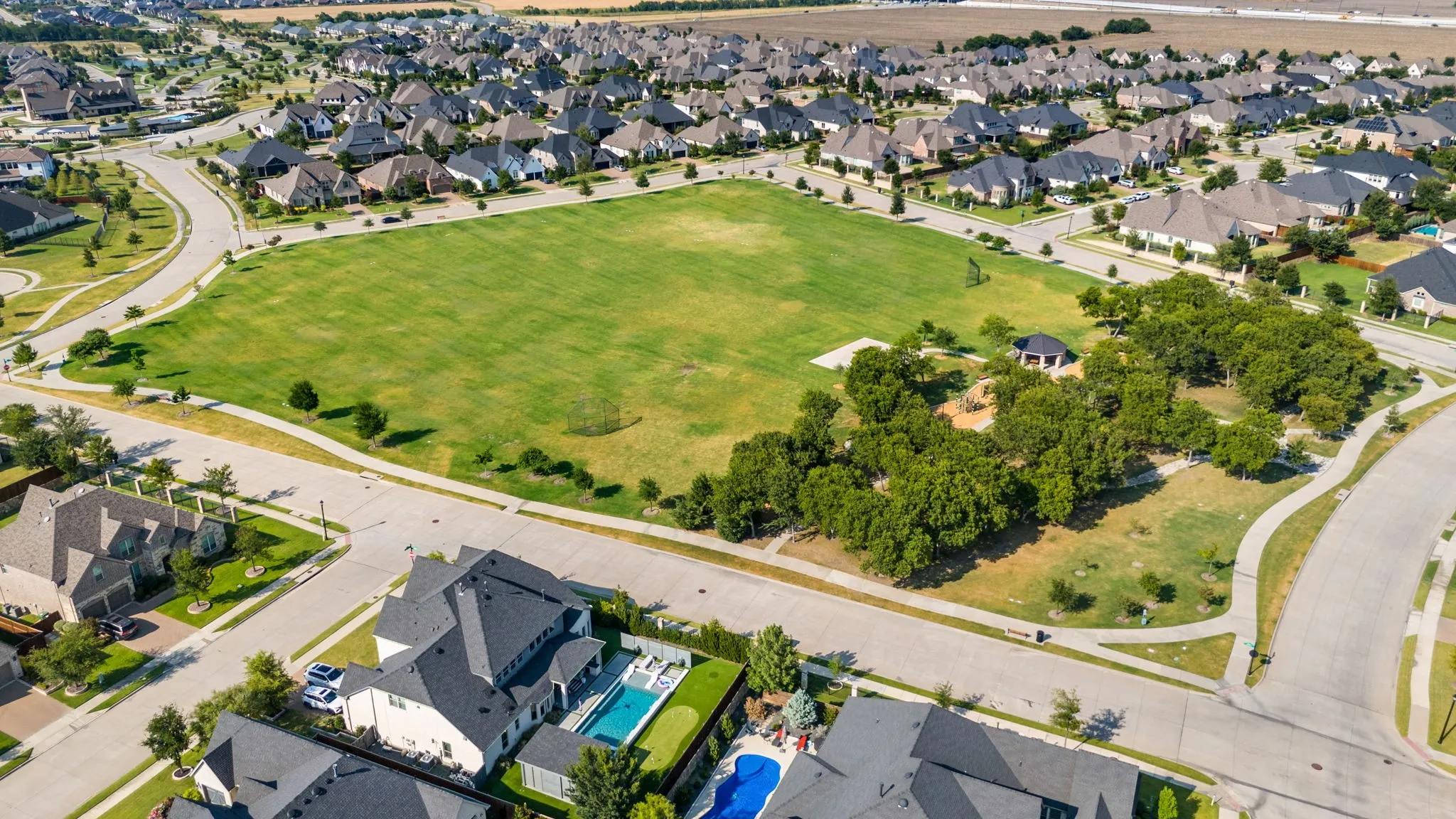 Aerial presentation of the neighborhood featuring a large central green space with mature trees and a gazebo