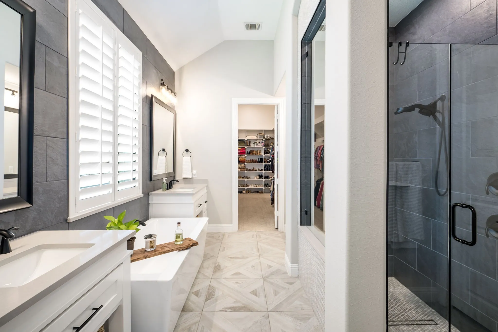 Spa-inspired primary bathroom featuring dual vanities with white cabinetry, quartz countertops, and brushed nickel fixtures