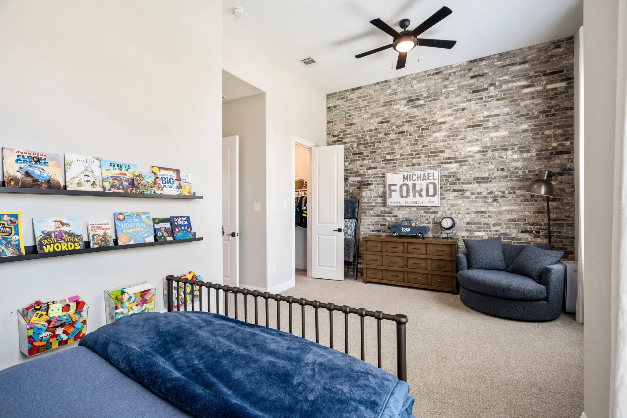Spacious bedroom featuring a black metal bed frame, soft blue bedding, and neutral carpet flooring
