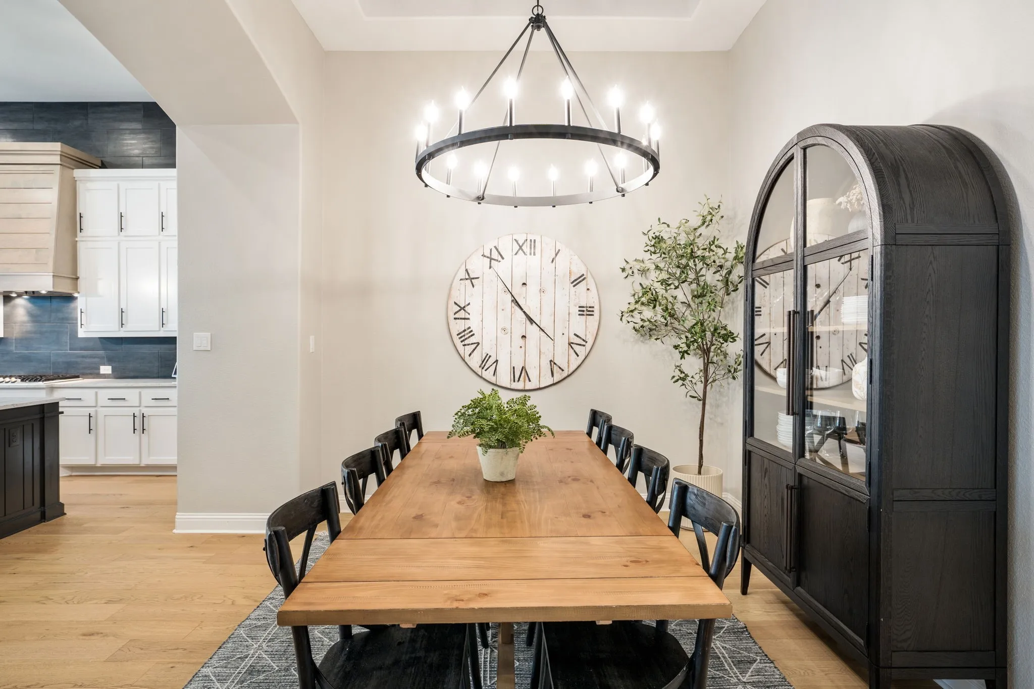 Elegant dining room featuring a solid wood harvest table, black Windsor-style chairs, and wide-plank wood-finish flooring