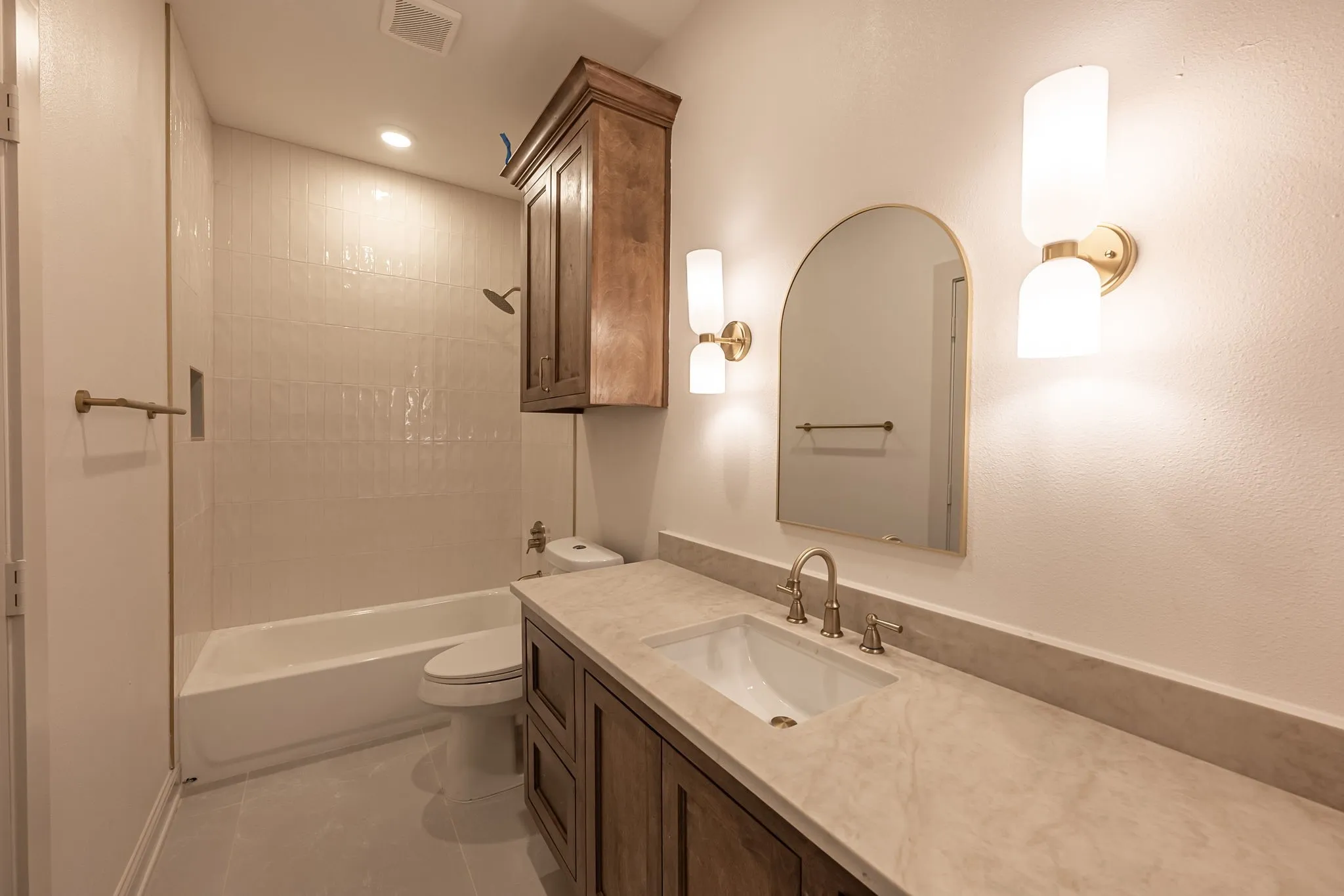 Built-in vanity with a stone countertop, undermount sink, and wall-mounted sconces