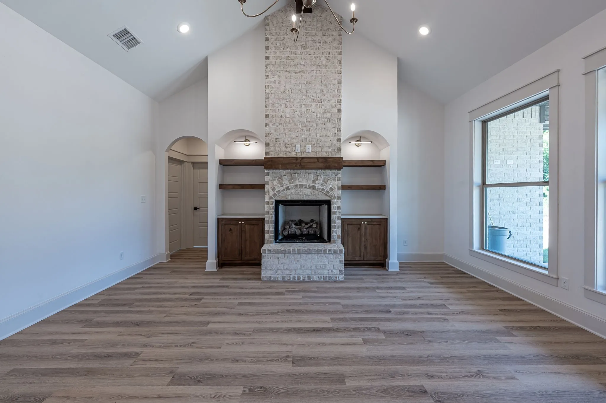 Spacious great room showcasing soaring vaulted ceilings, recessed lighting, and wide-plank wood-finish flooring