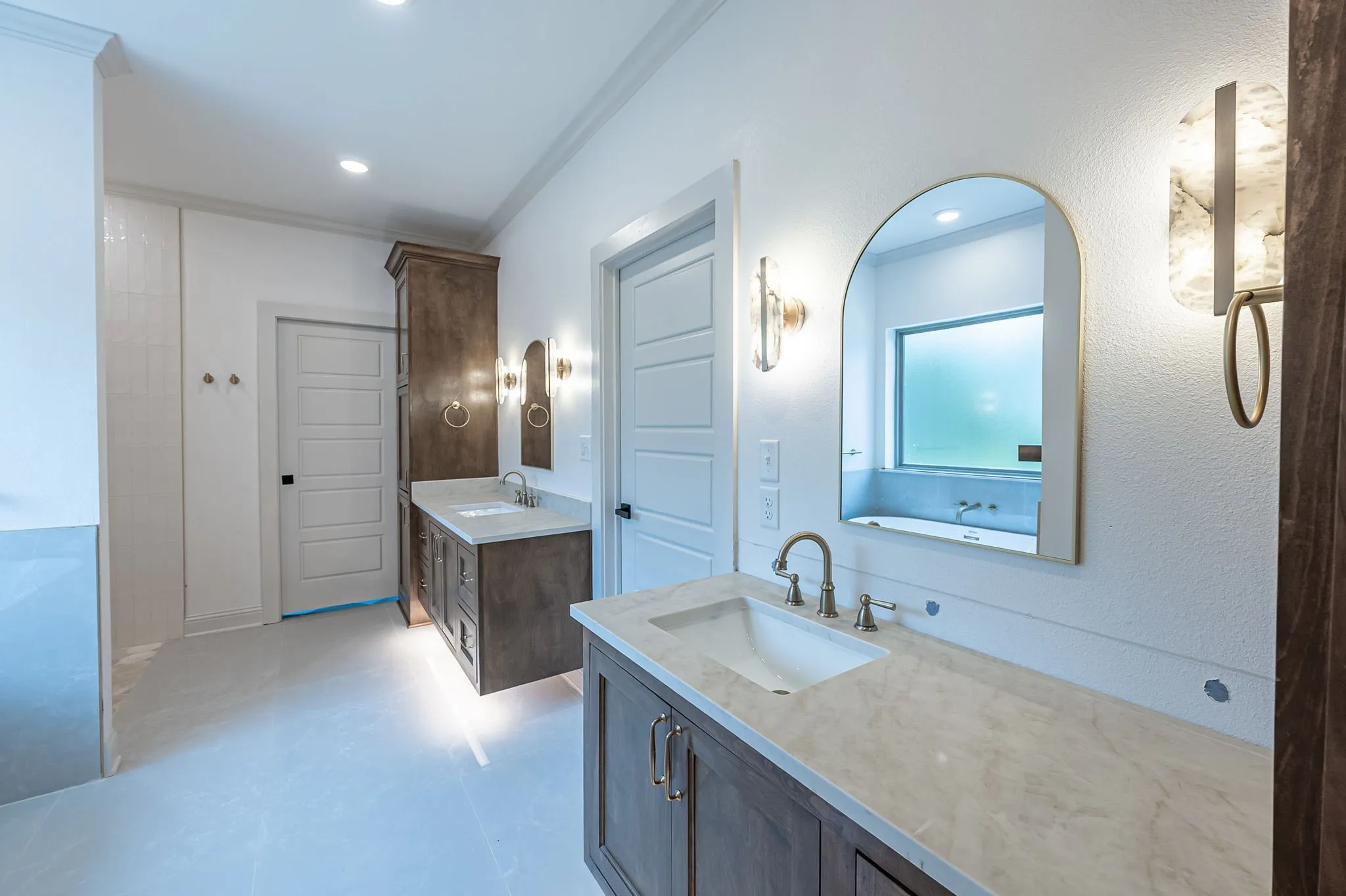 Dual vanity with wood-finish cabinetry, light-toned countertops, and undermount sinks