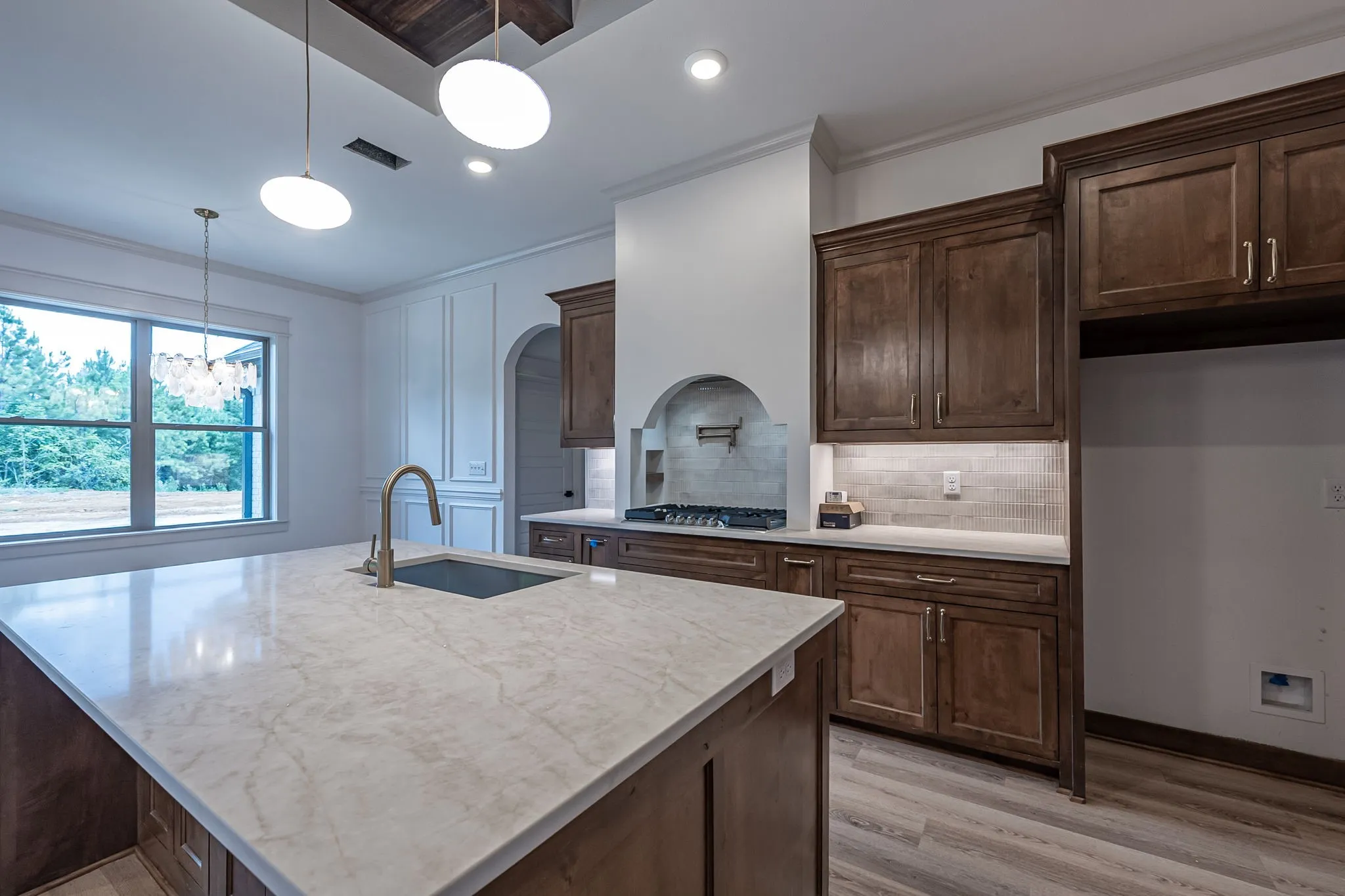 Kitchen island with a large undermount sink, gooseneck faucet, and light-toned countertop