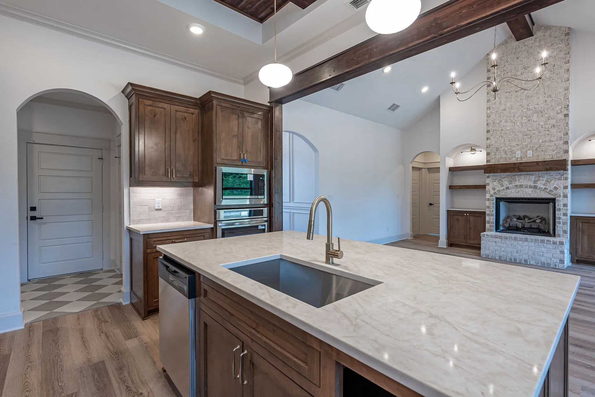 Gourmet kitchen featuring a large island with an undermount sink, built-in stainless steel appliances, and wood cabinetry