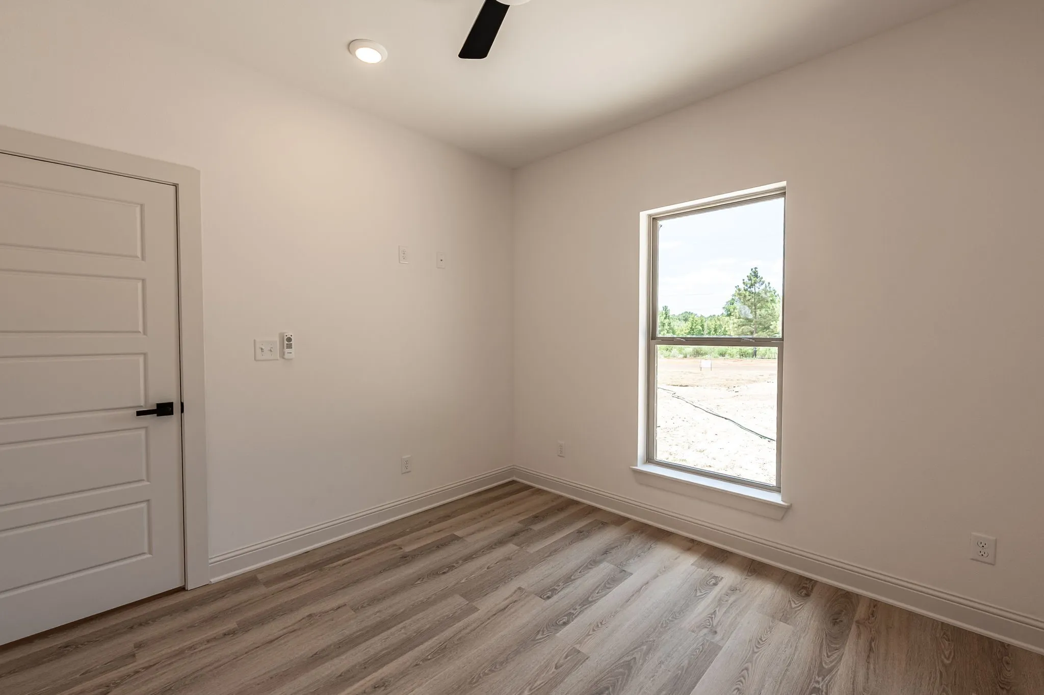 Recessed ceiling lighting, a modern ceiling fan, and wood-finish flooring