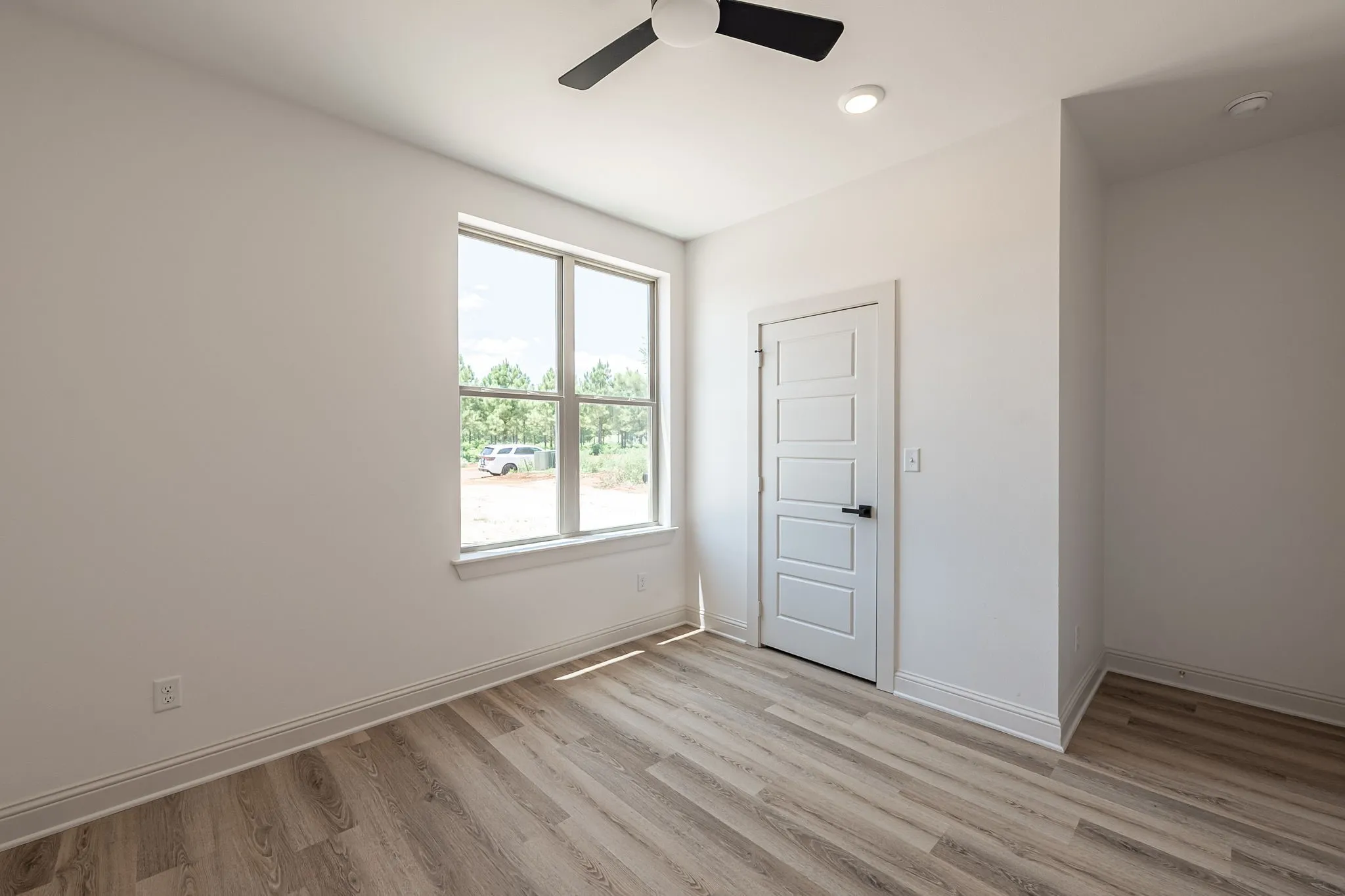 Expansive window, wood-finish flooring, recessed lighting, and a contemporary ceiling fan